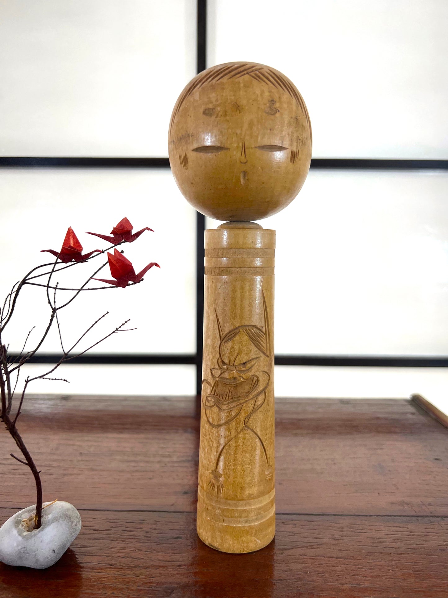 kokeshi poupée japonaise en bois gravé d'une visage de démon sur le corps