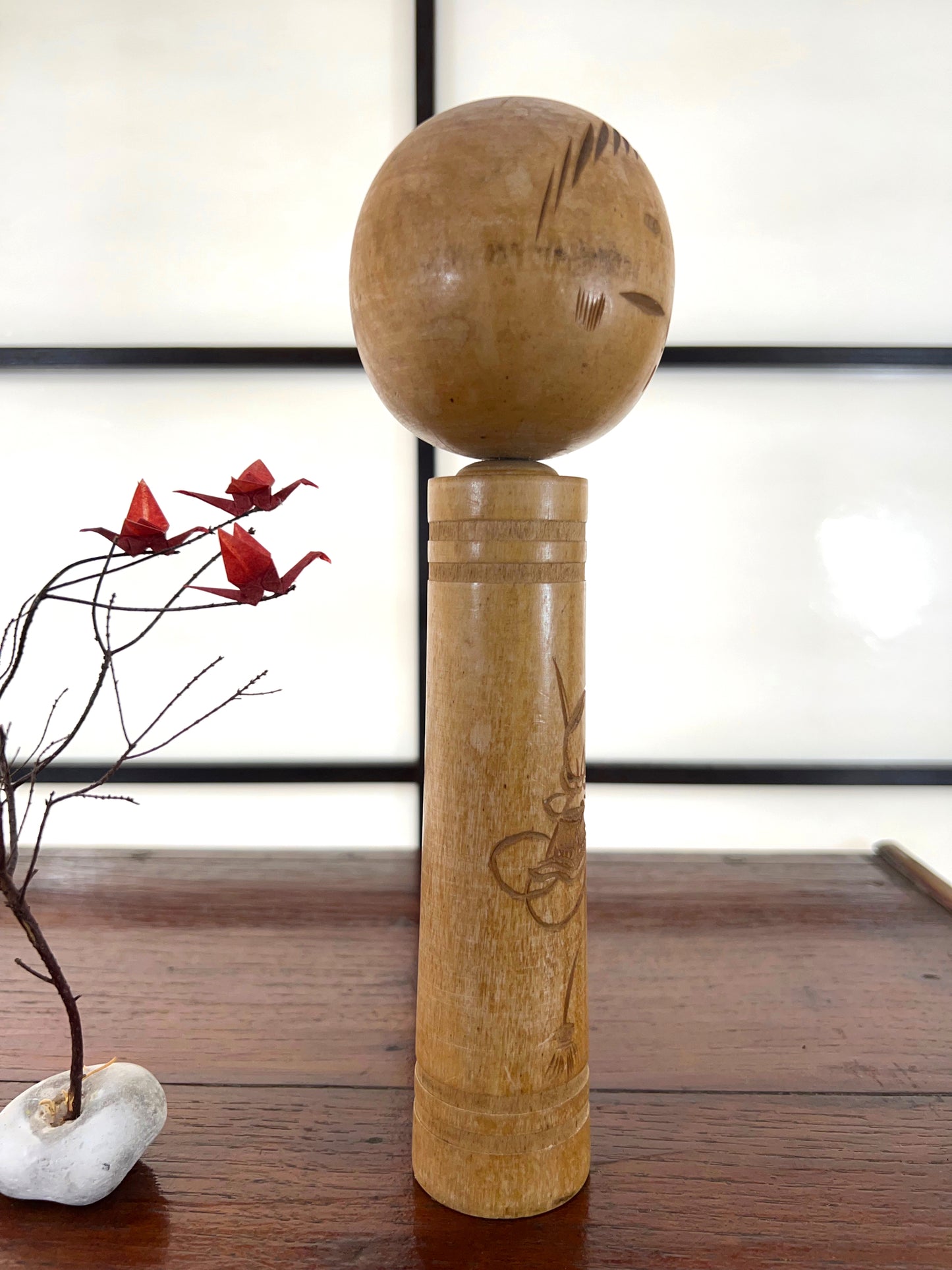 kokeshi poupée japonaise en bois gravé d'une visage de démon sur le corps, profil droit
