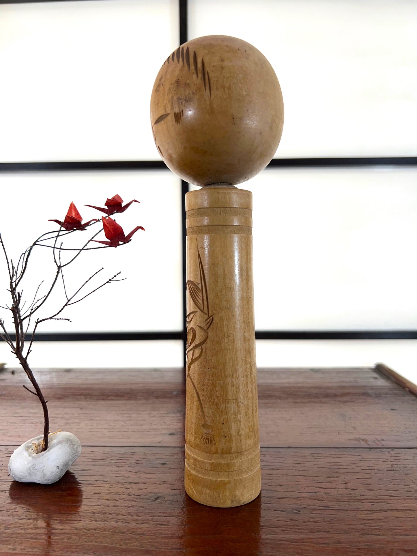 kokeshi poupée japonaise en bois gravé d'une visage de démon sur le corps, profil gauche