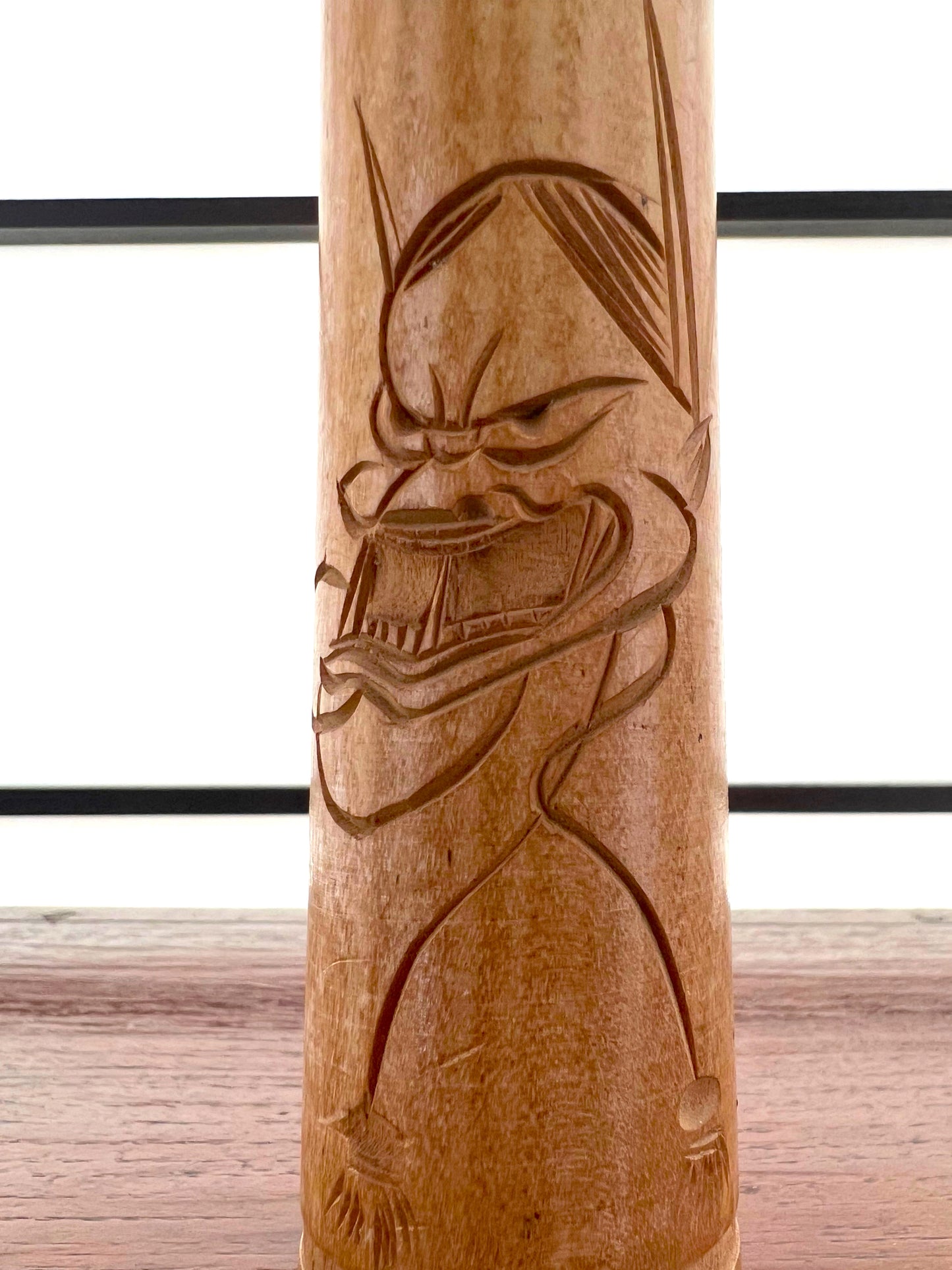 kokeshi poupée japonaise en bois gravé d'une visage de démon sur le corps, gros plan sur le démon gravé