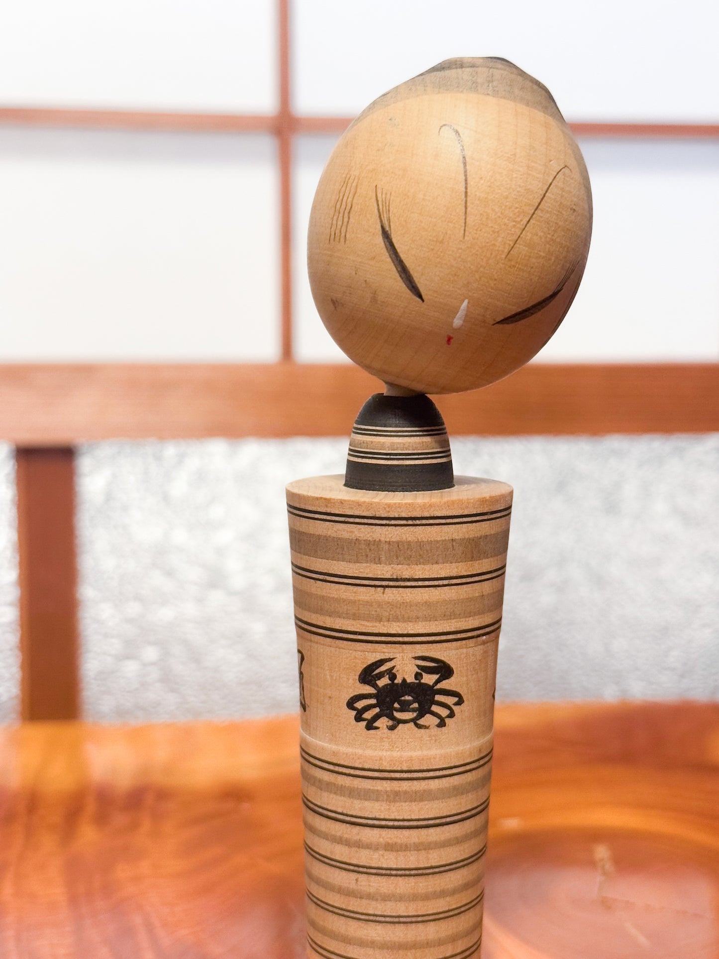 kokeshi sumi-e de Hatsutaro rayé avec motif crabe et coquillages, gros plan sur la tête