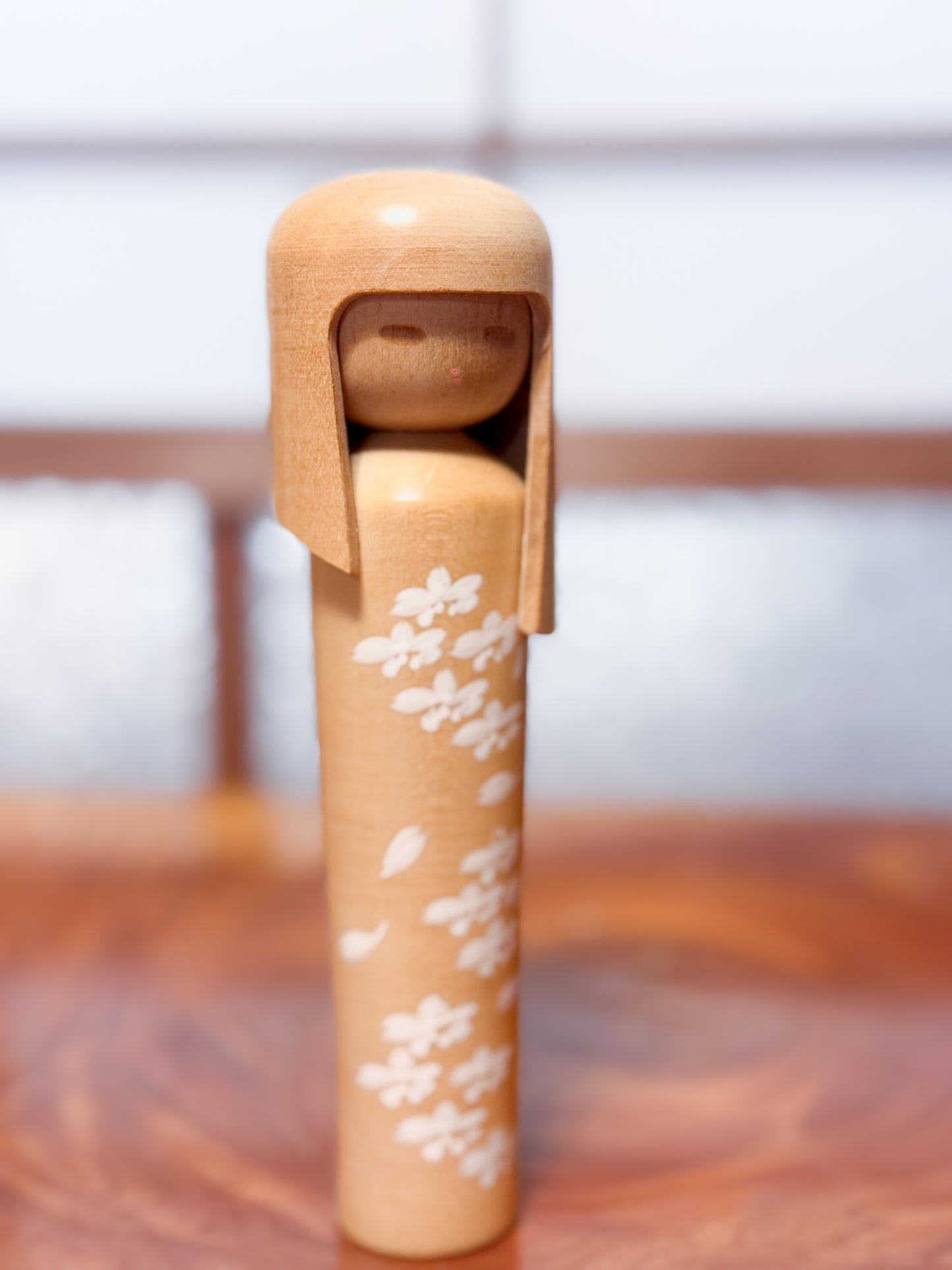 kokeshi de Miyashita Mihutsu en bois naturel avec fleurs blanches peintes et longue chevelure, vu de 3/4 droite