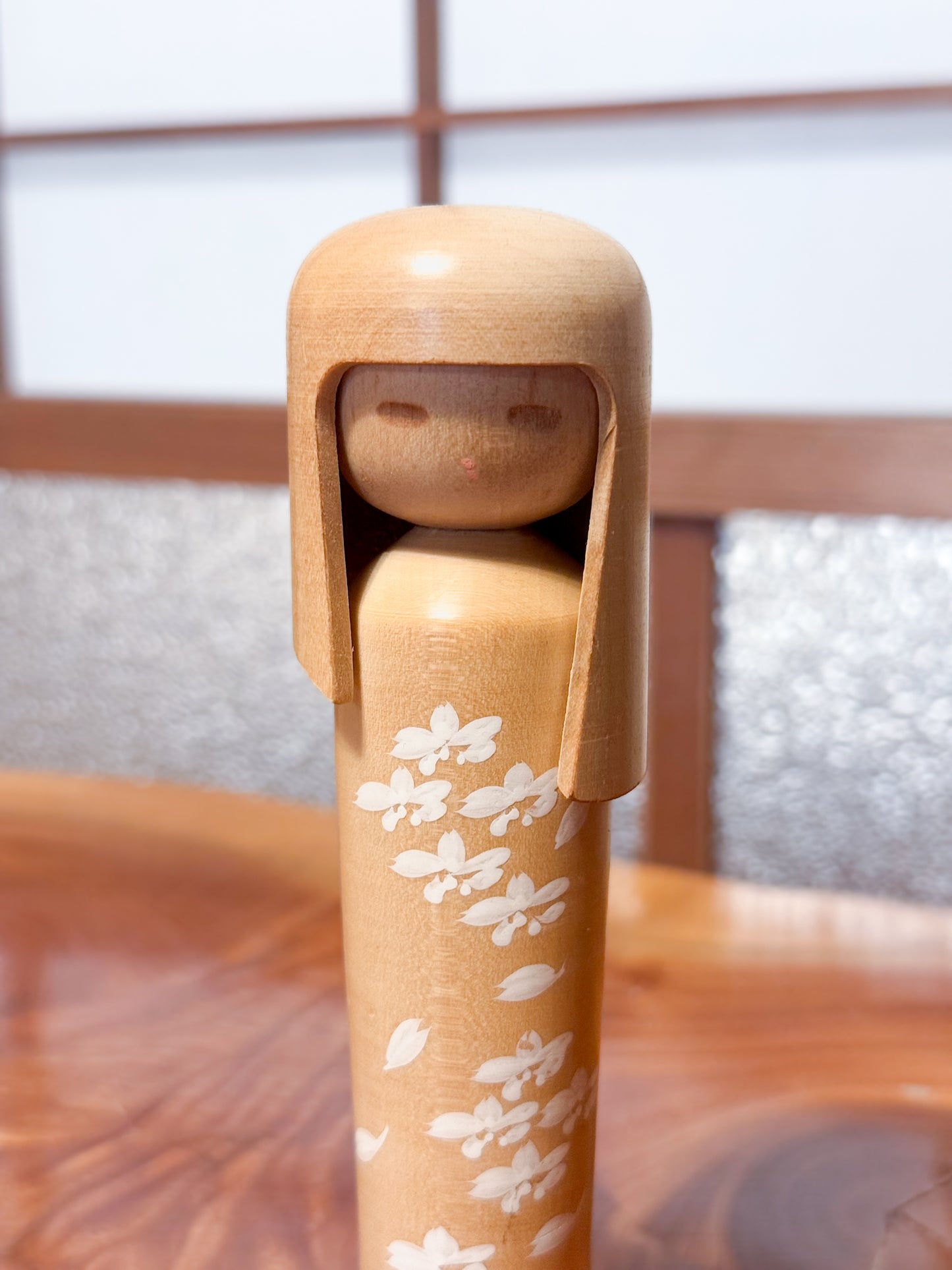 kokeshi de Miyashita Mihutsu en bois naturel avec fleurs blanches peintes et longue chevelure, gros plan sur le visage