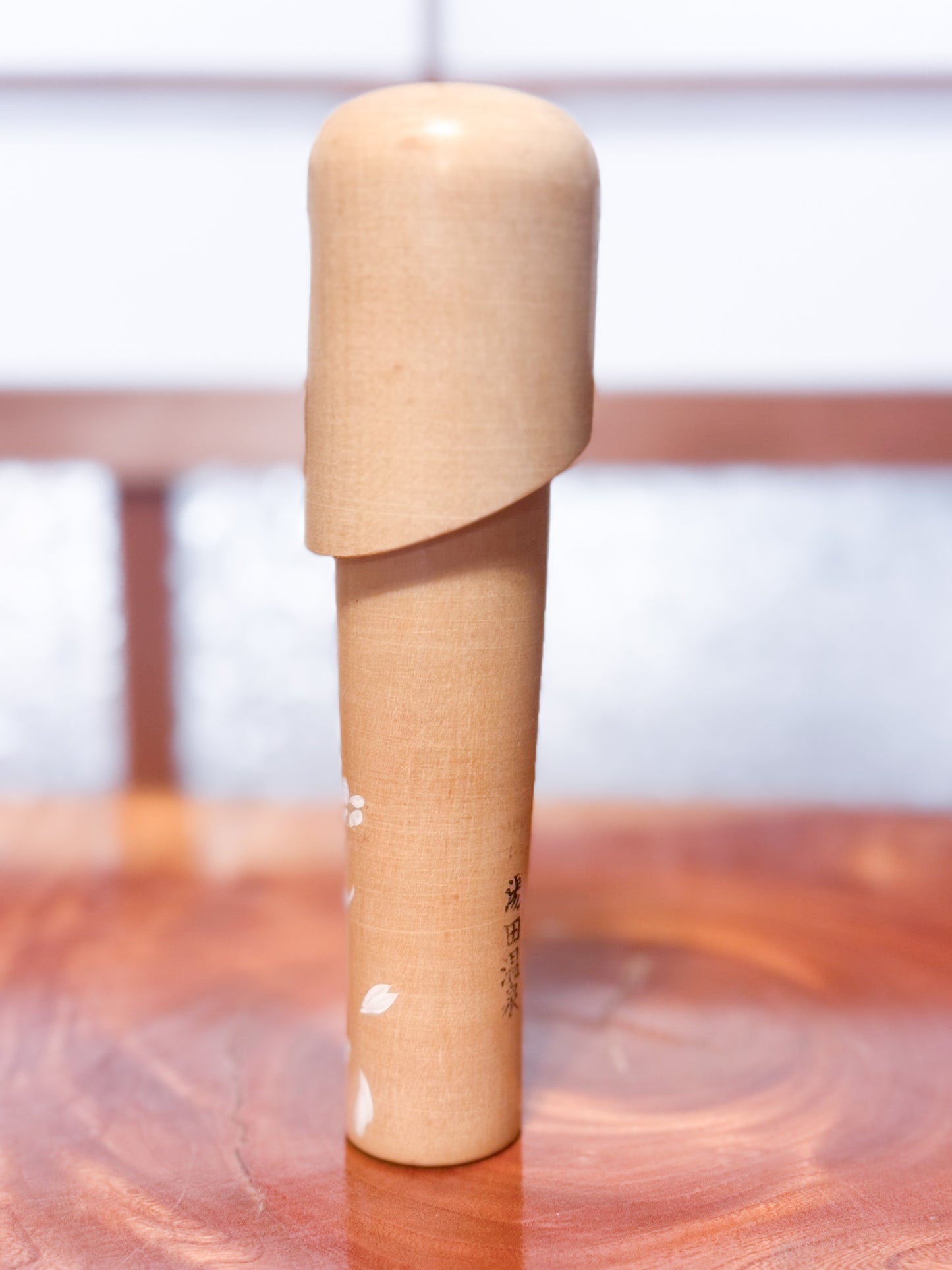 kokeshi de Miyashita Mihutsu en bois naturel avec fleurs blanches peintes et longue chevelure, vu de dos