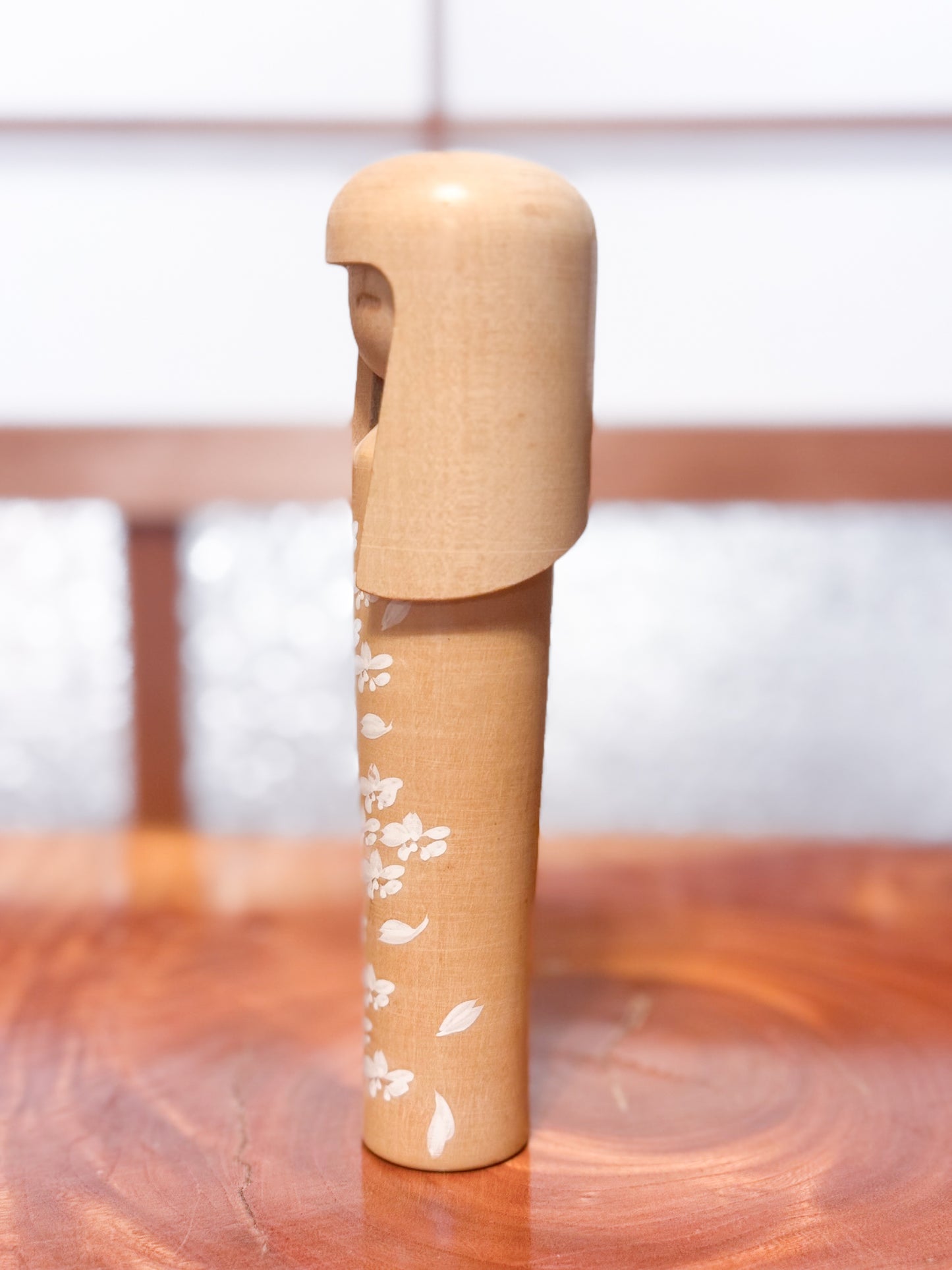 kokeshi de Miyashita Mihutsu en bois naturel avec fleurs blanches peintes et longue chevelure, profil gauche