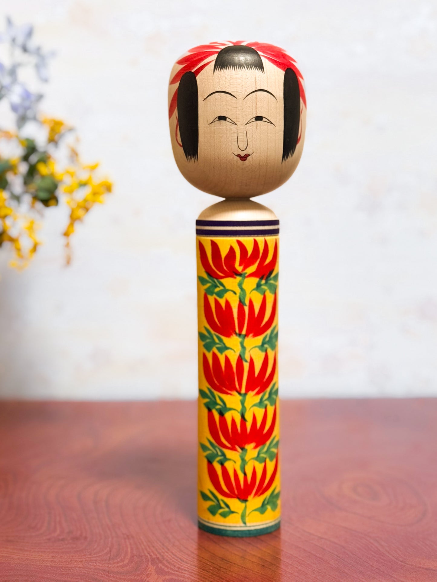 kokeshi traditionelle motif chrysanthème rouge sur fond jaune, visage souriant