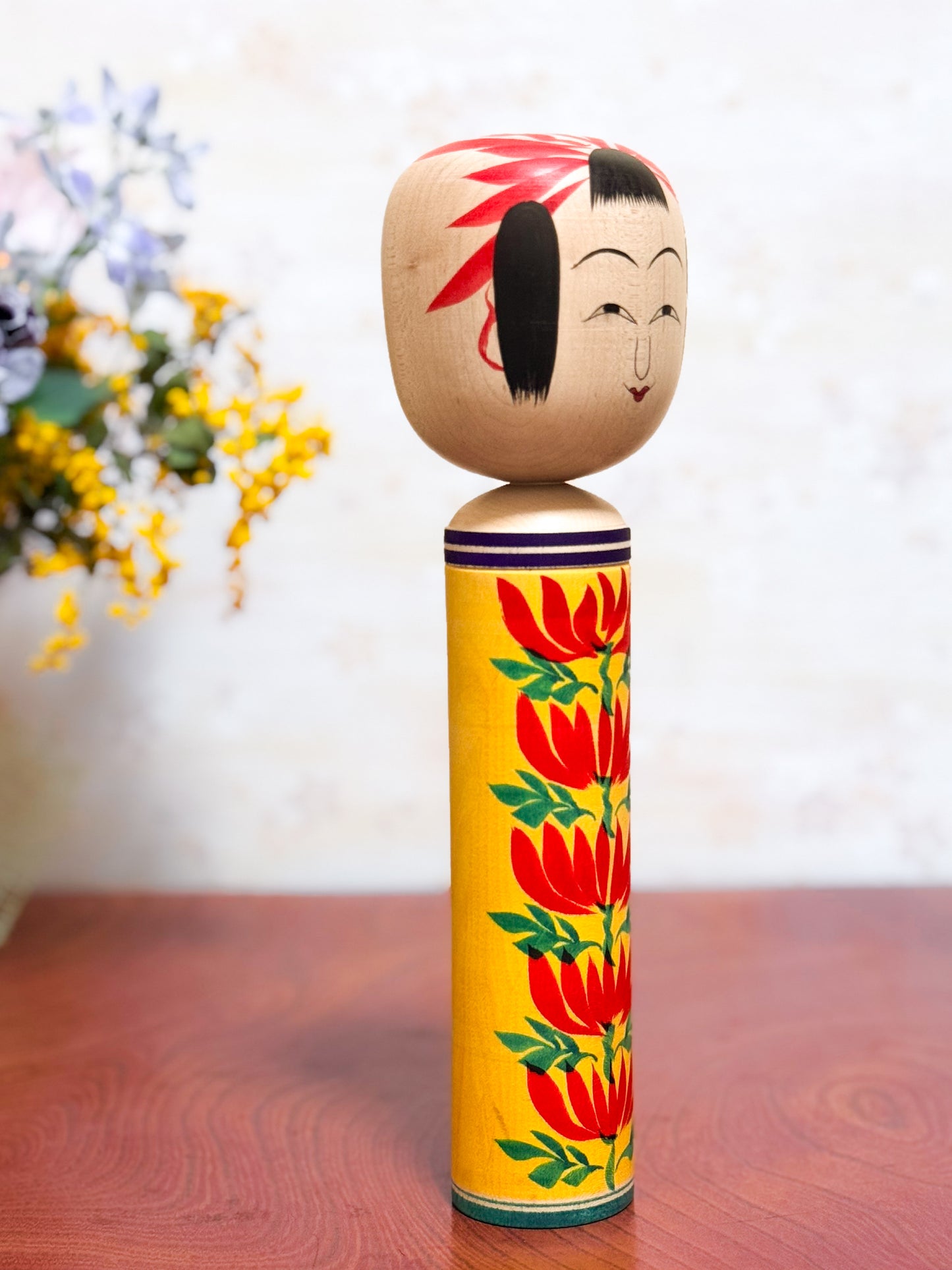 kokeshi traditionelle motif chrysanthème rouge sur fond jaune, visage souriant, profil droit