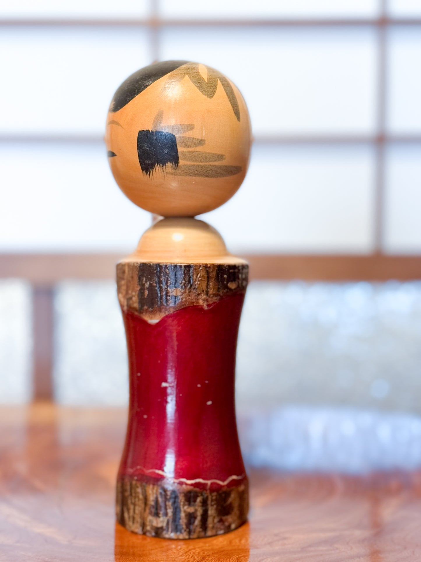 Kokeshi en bois brut avec laque rouge et kanji "zen" doré, profil droit
