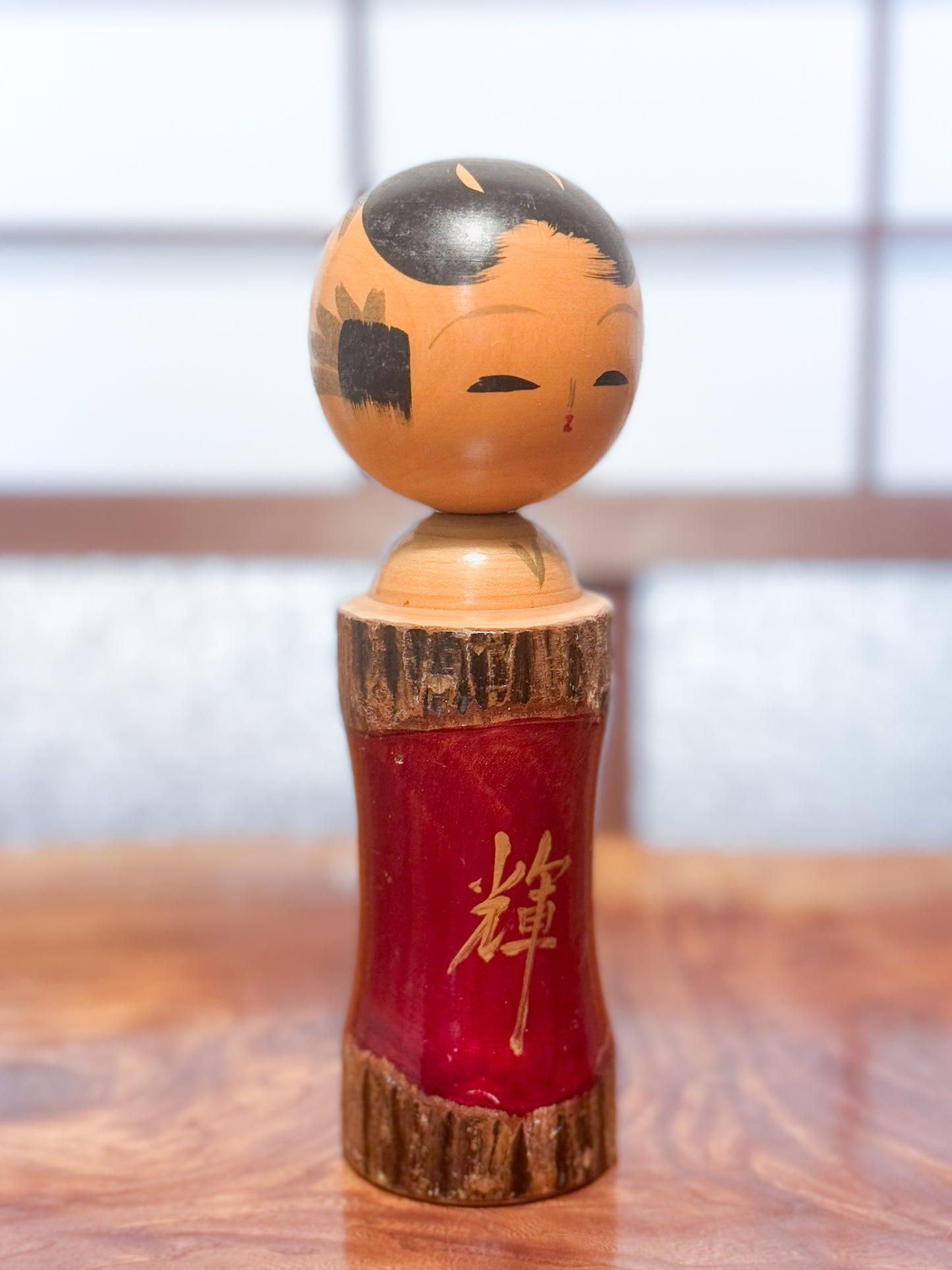 Kokeshi en bois brut avec laque rouge et kanji "zen" doré, vu de 3/4 gauche