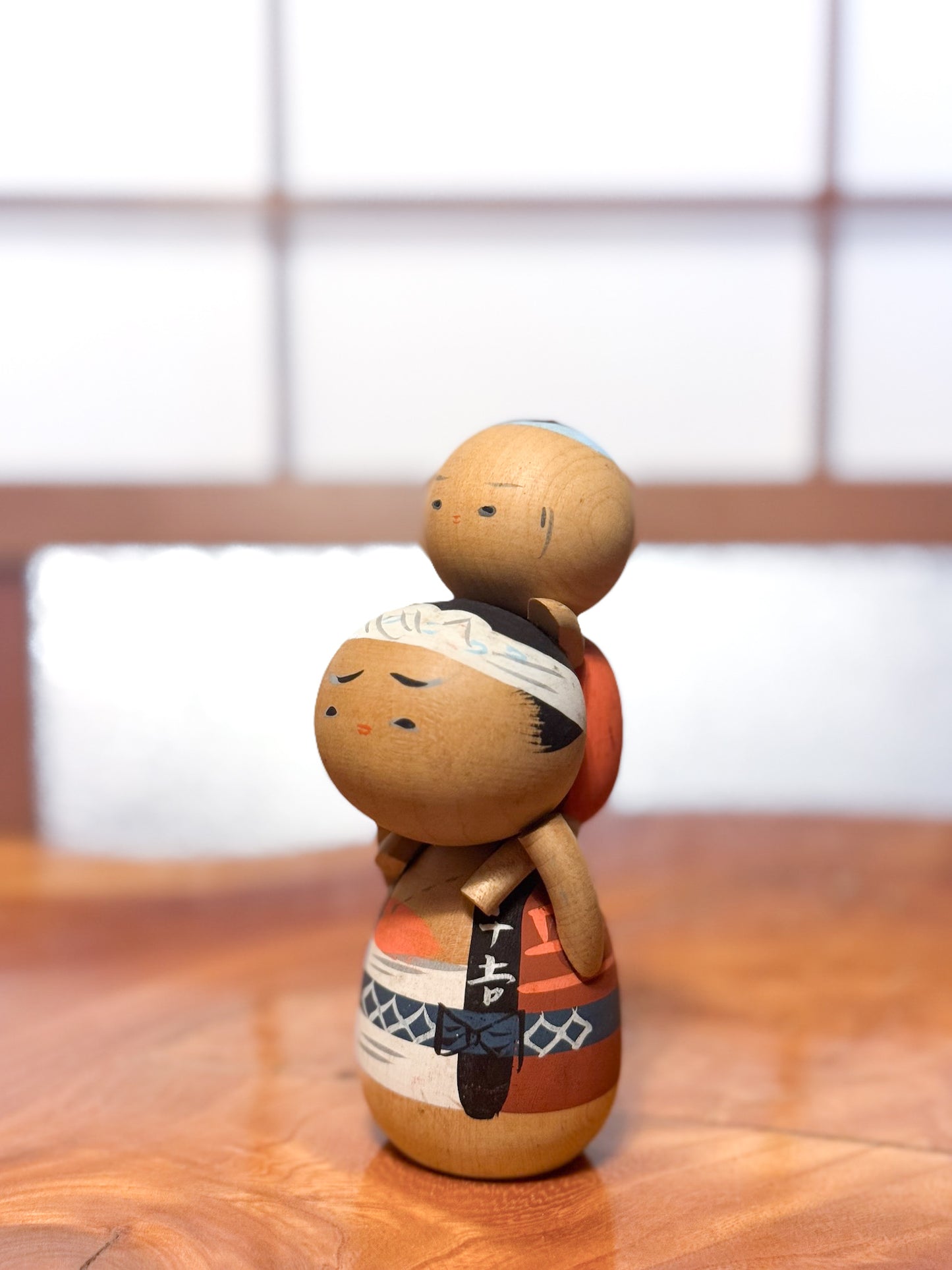 kokeshi japonaise vintage père portant enfant sur les épaules, vu de 3/4 gauche