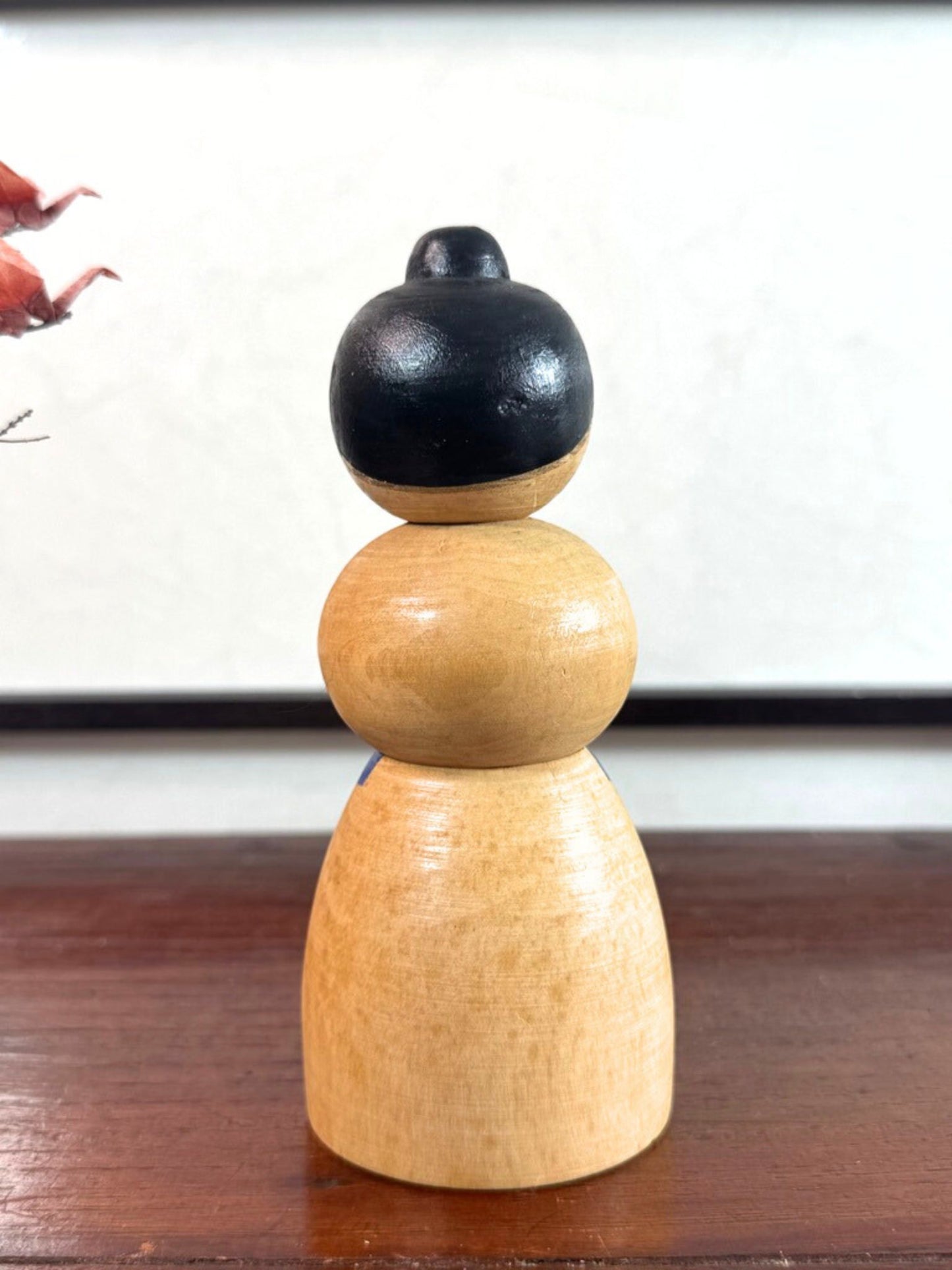 Kokeshi japonaise vintage représentant un sumo, en bois peint avec tablier au motif végétal stylisé, vu de dos