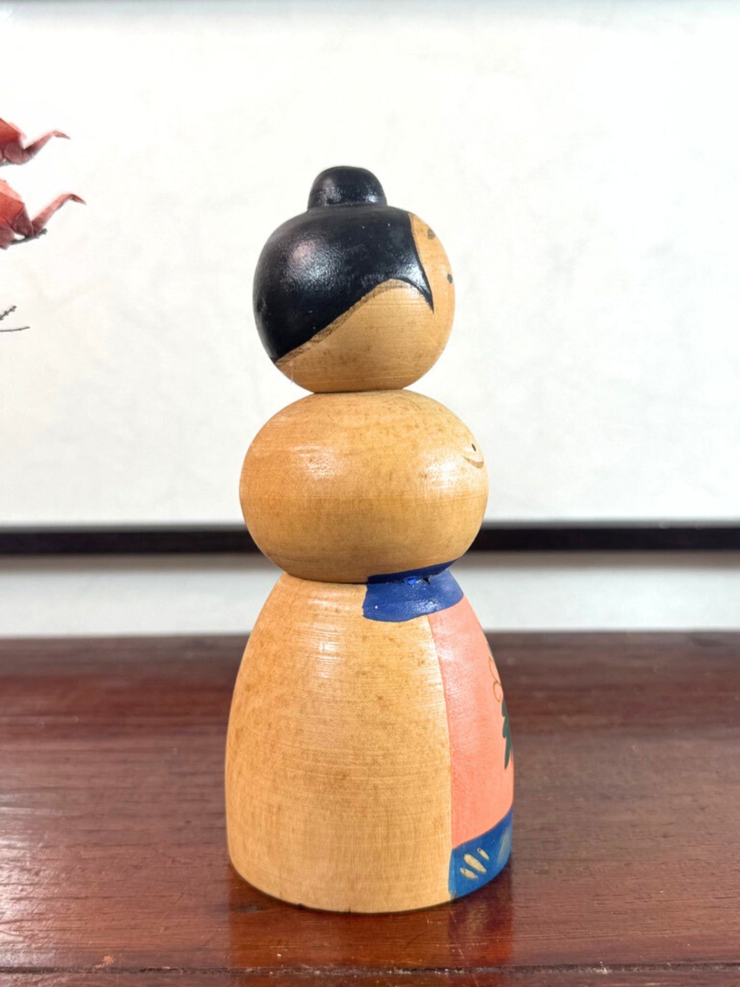 Kokeshi japonaise vintage représentant un sumo, en bois peint avec tablier au motif végétal stylisé, vu du profil droit