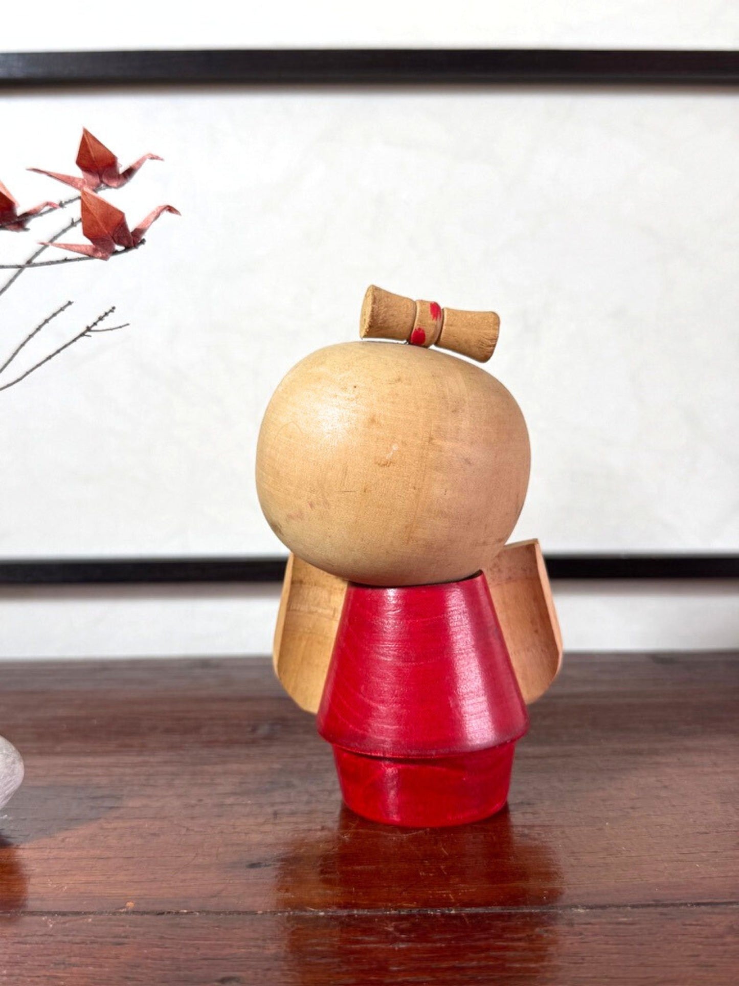 Kokeshi japonaise rouge avec fleurs, coiffée d’un nœud, signée Kazuo Takamizawa, vu de dos