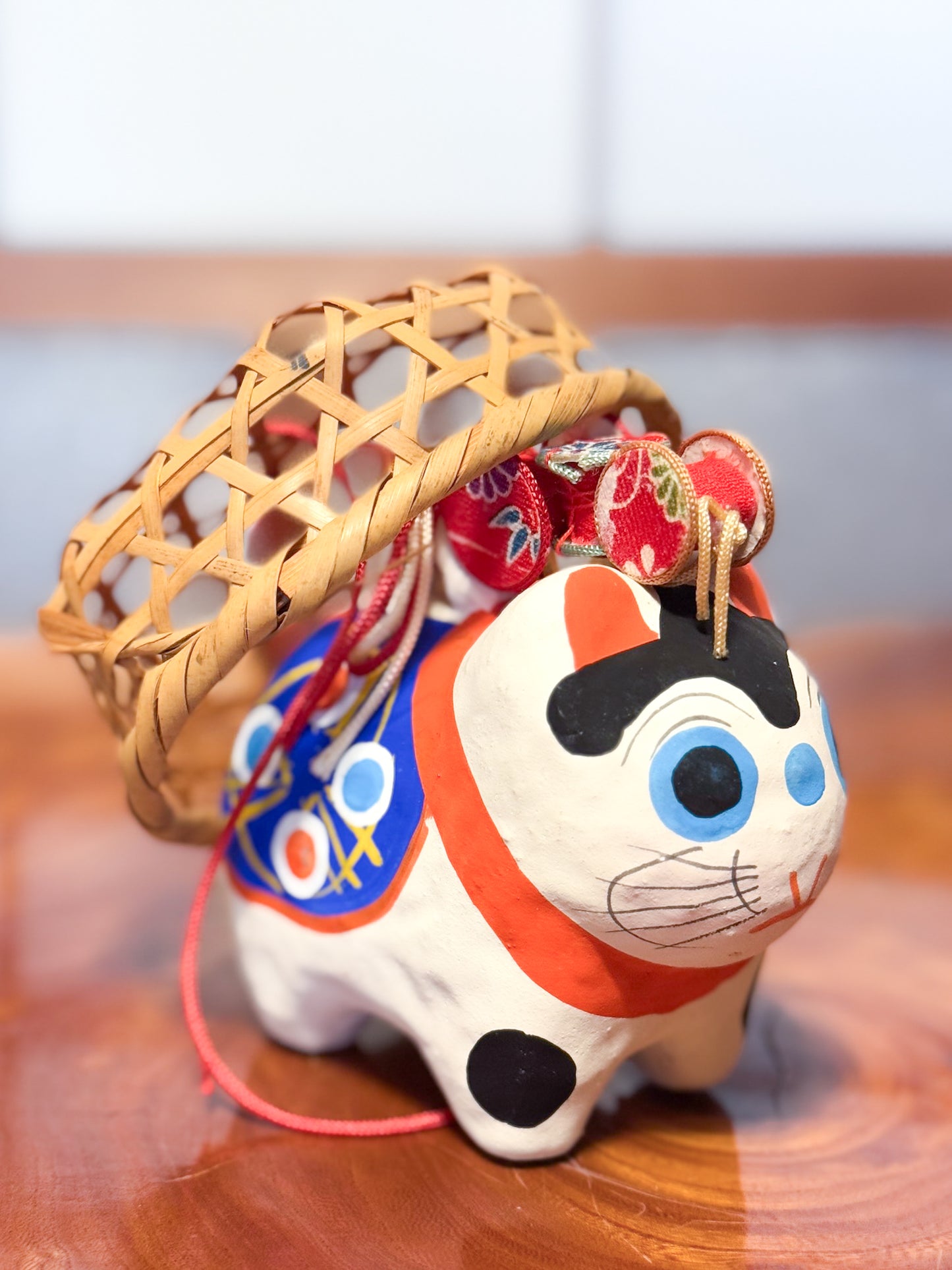 Figurine japonaise en papier mâché représentant un inu hariko blanc décoré, avec panier en bambou et tambours miniatures sur le dos, profil droit