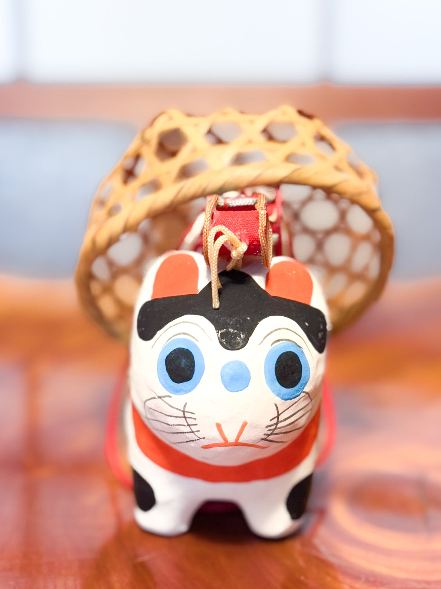 Figurine japonaise en papier mâché représentant un inu hariko blanc décoré, avec panier en bambou et tambours miniatures sur le dos, gros plan sur la tête