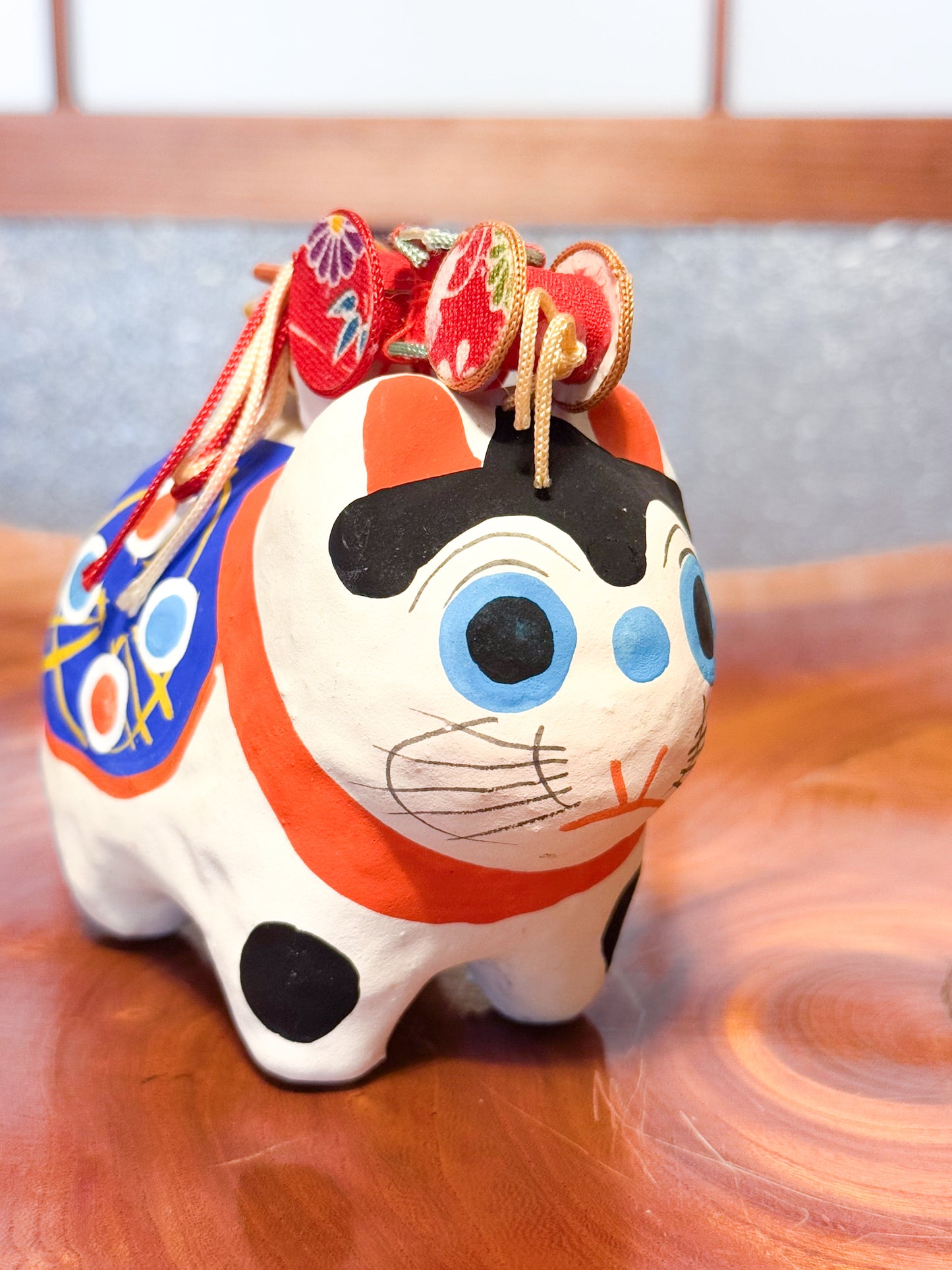 Figurine japonaise en papier mâché représentant un inu hariko blanc décoré, avec panier en bambou et tambours miniatures sur le dos, profil droit