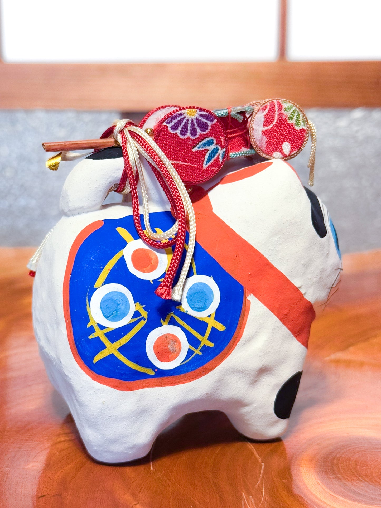 Figurine japonaise en papier mâché représentant un inu hariko blanc décoré, avec panier en bambou et tambours miniatures sur le dos, motif peint