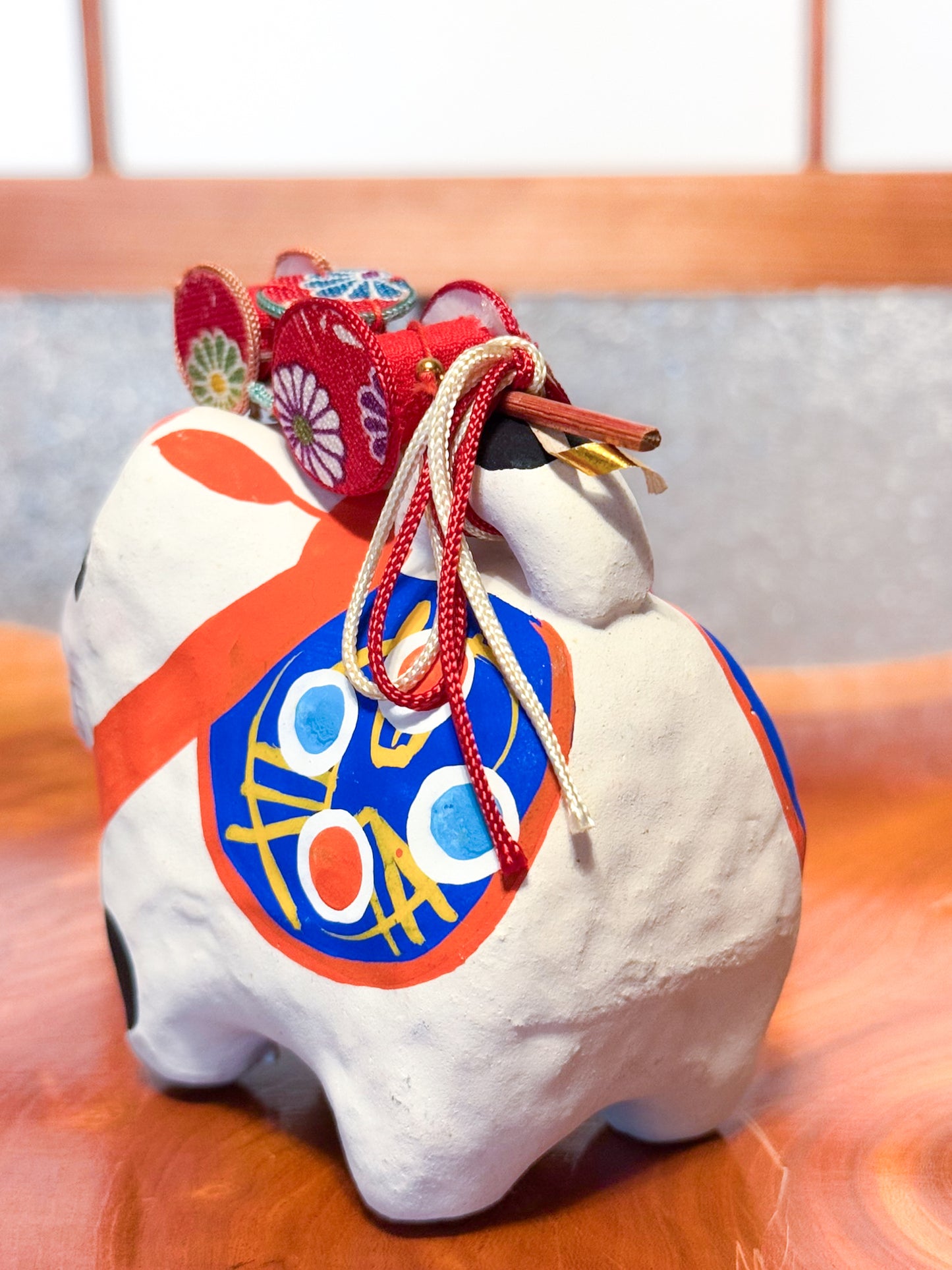 Figurine japonaise en papier mâché représentant un inu hariko blanc décoré, avec panier en bambou et tambours miniatures sur le dos, profil gauche