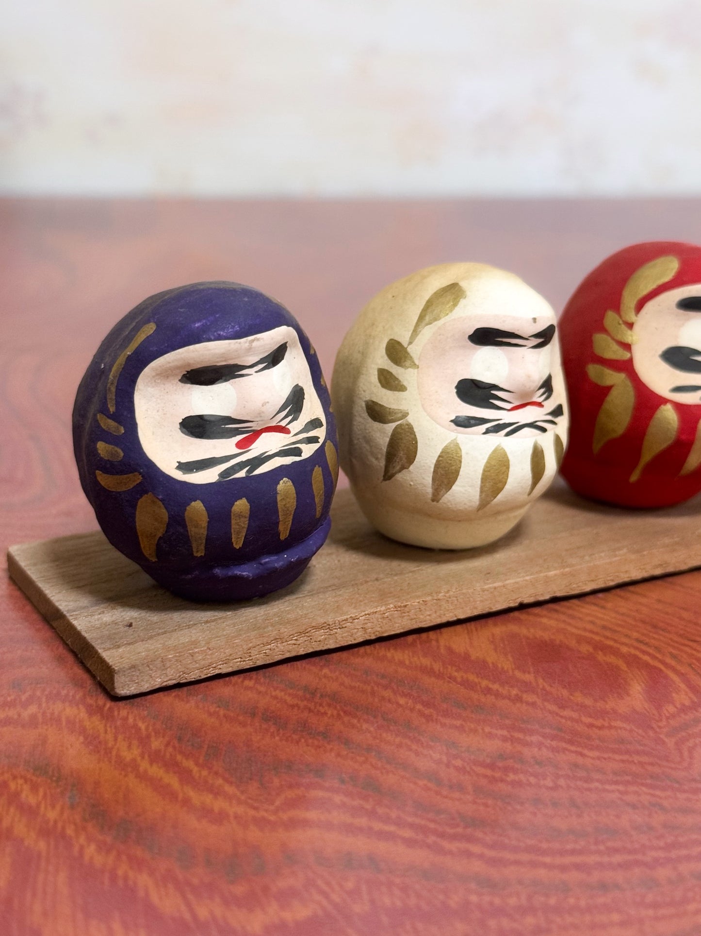 Ensemble de cinq Daruma colorés sur socle en bois