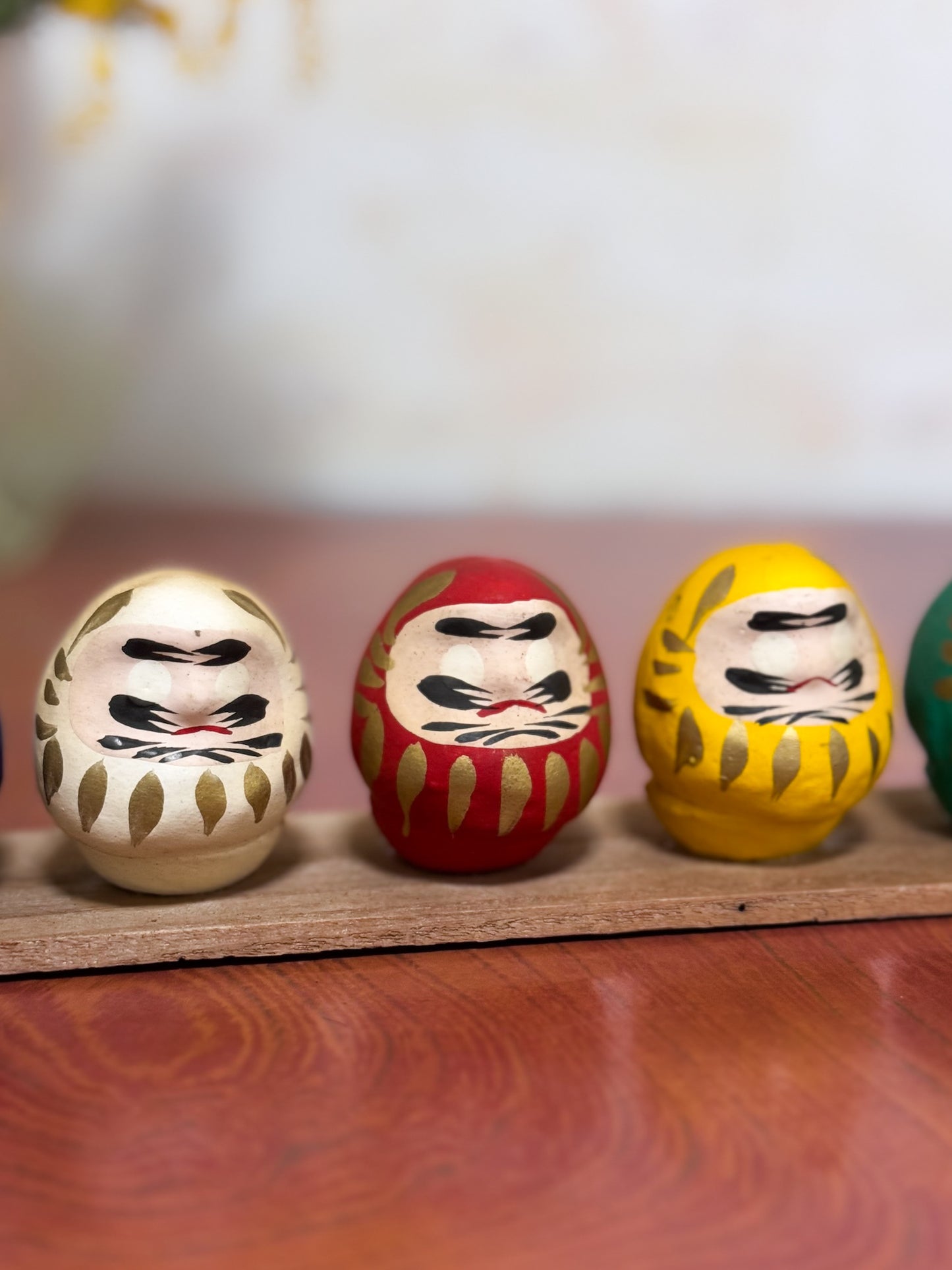 Ensemble de cinq Daruma colorés sur socle en bois