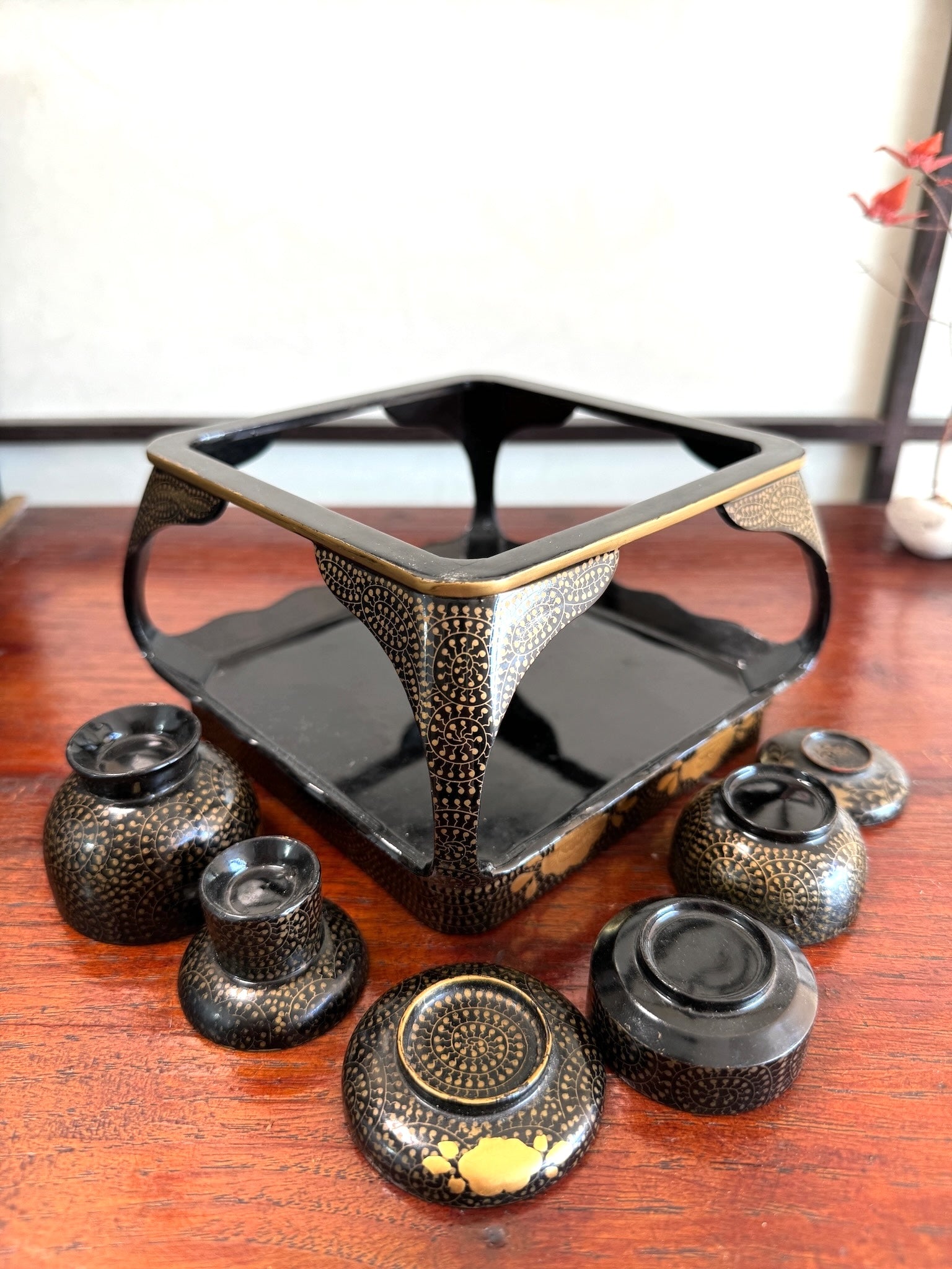 Ensemble miniature japonais comprenant un plateau en laque noire et rouge avec décor doré et plusieurs petits bols et coupes assortis, vu de dessous