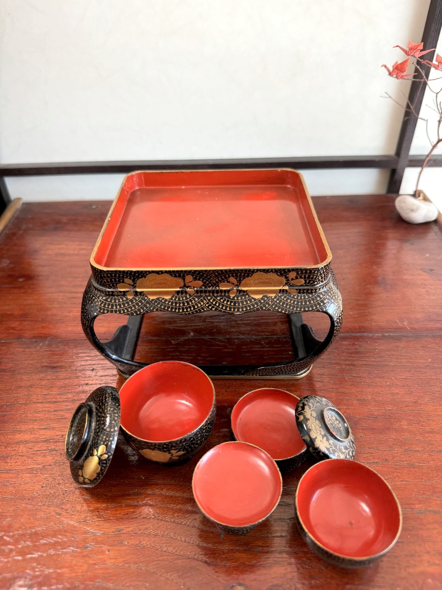 Ensemble miniature japonais comprenant un plateau en laque noire et rouge avec décor doré et plusieurs petits bols et coupes assortis, vu de dessus