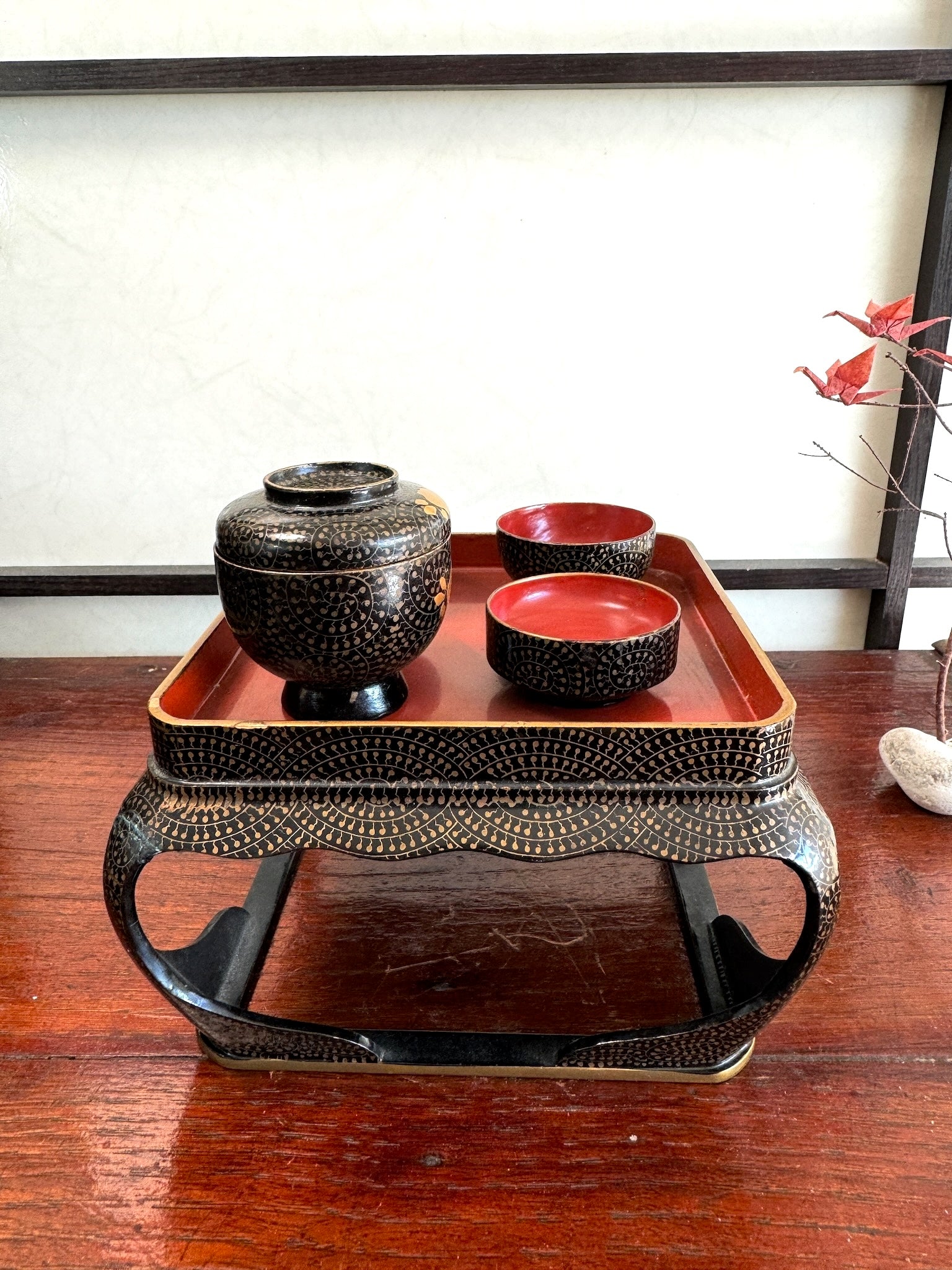 Ensemble miniature japonais comprenant un plateau en laque noire et rouge avec décor doré et plusieurs petits bols et coupes assortis, vu côté droit
