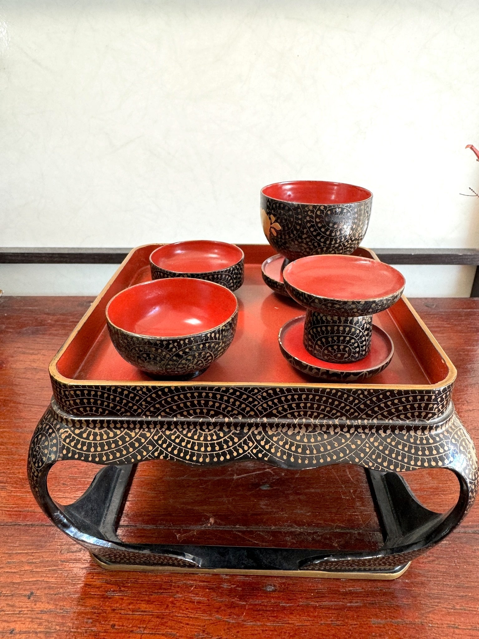 Ensemble miniature japonais comprenant un plateau en laque noire et rouge avec décor doré et plusieurs petits bols et coupes assortis, vu de l'arrière