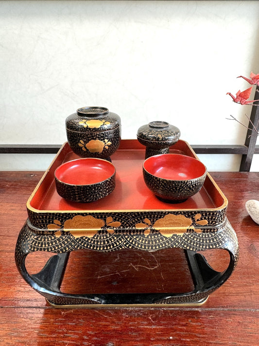 Ensemble miniature japonais comprenant un plateau en laque noire et rouge avec décor doré et plusieurs petits bols et coupes assortis au motif fleurs et arabesques dorées