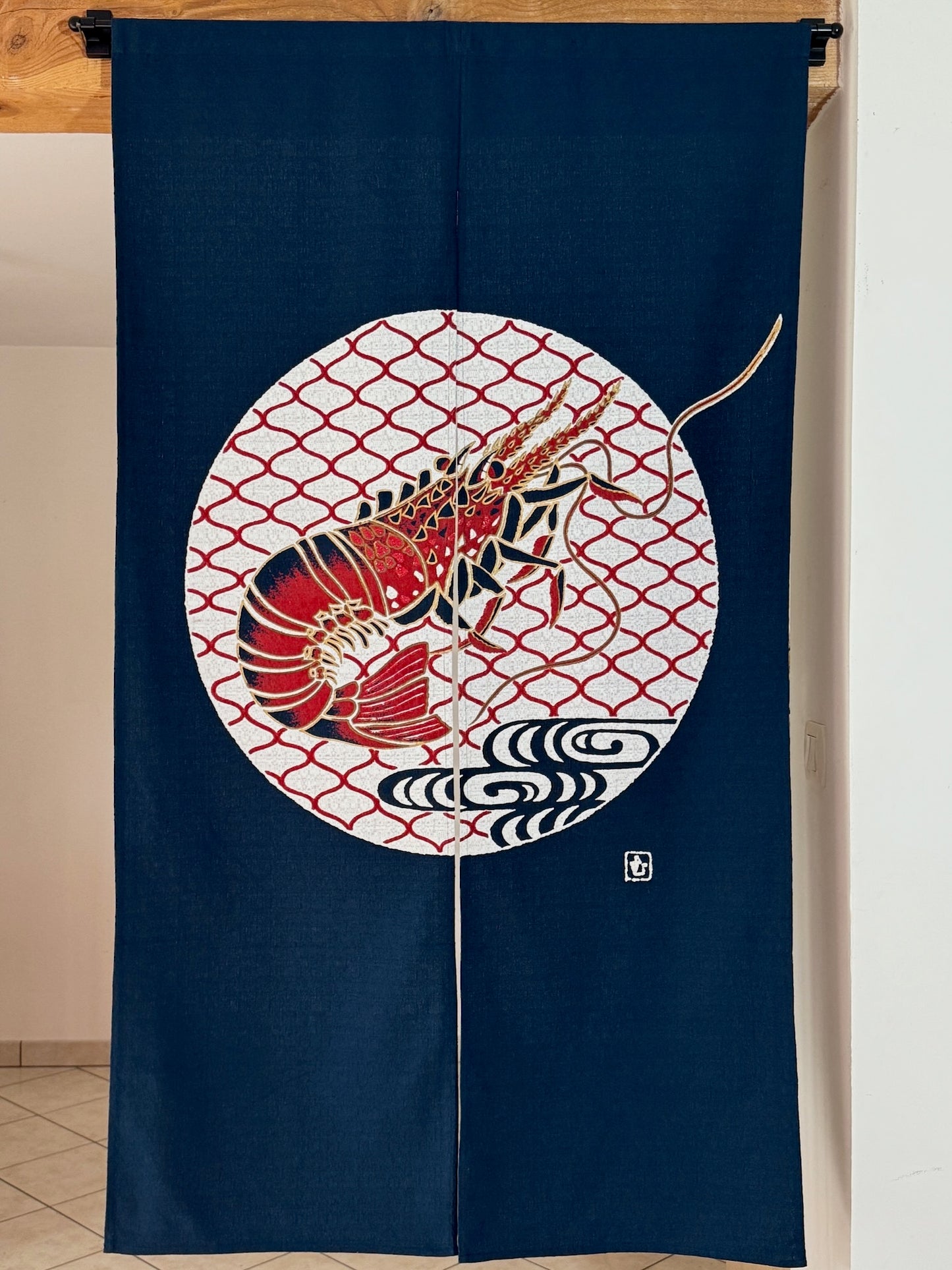 Noren japonais bleu marine avec motif de crevette, symbole de longévité, au centre d'un cercle blanc et rouge.