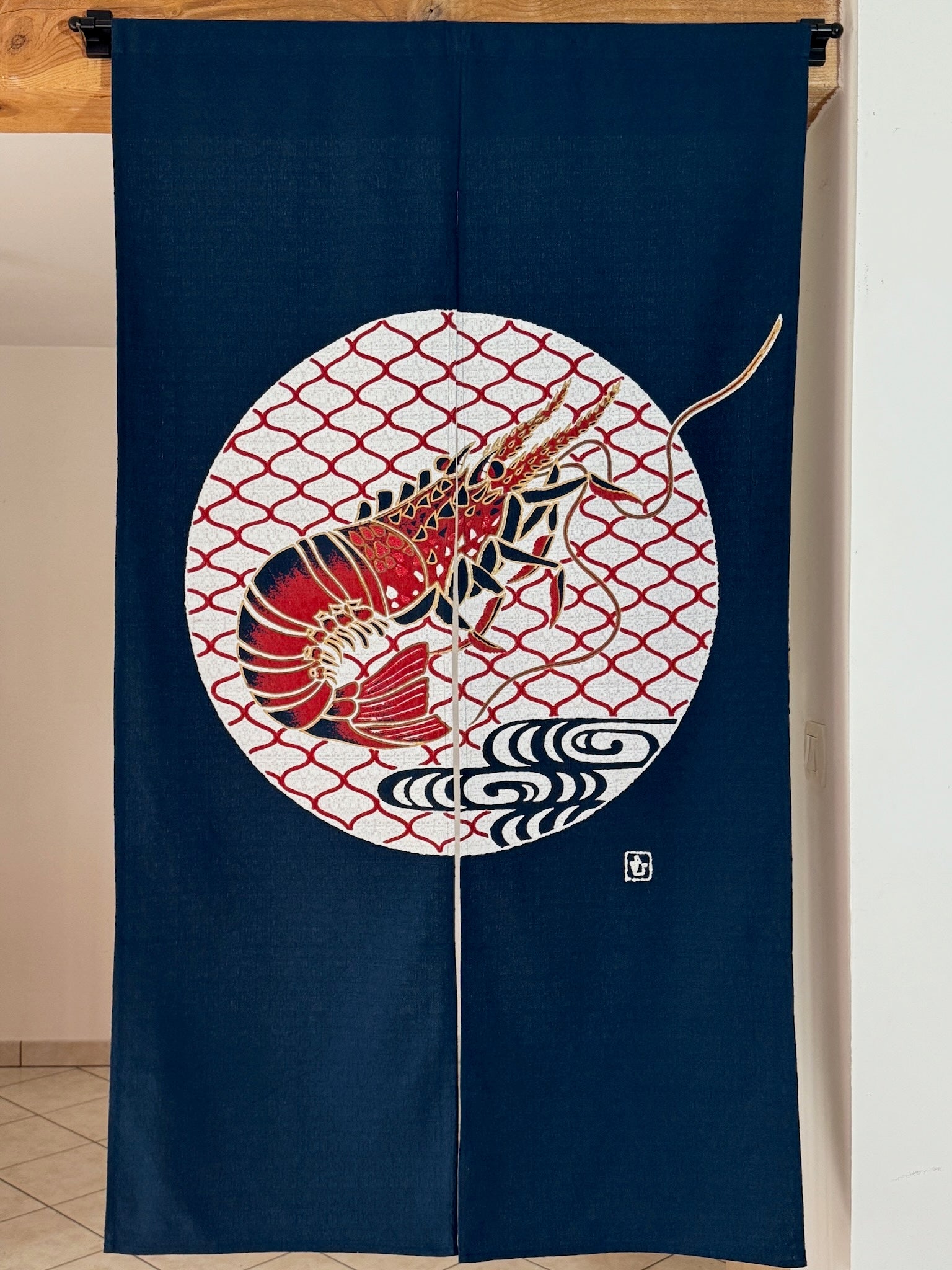 Noren japonais bleu marine avec motif de crevette, symbole de longévité, au centre d'un cercle blanc et rouge.
