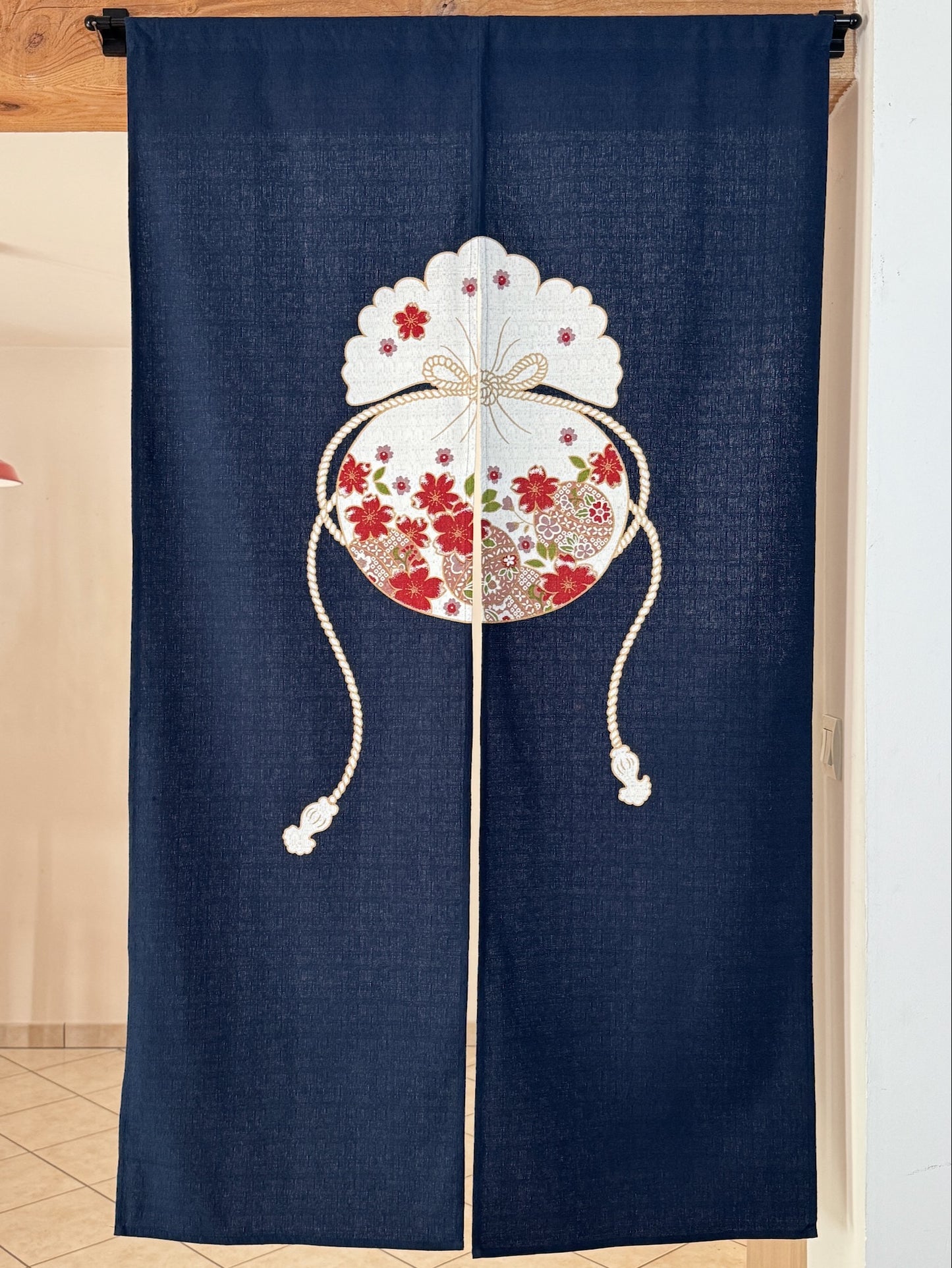 Noren japonais avec une pochette, fleurs de cerisier rouges et blanches, et balles temari sur fond bleu.