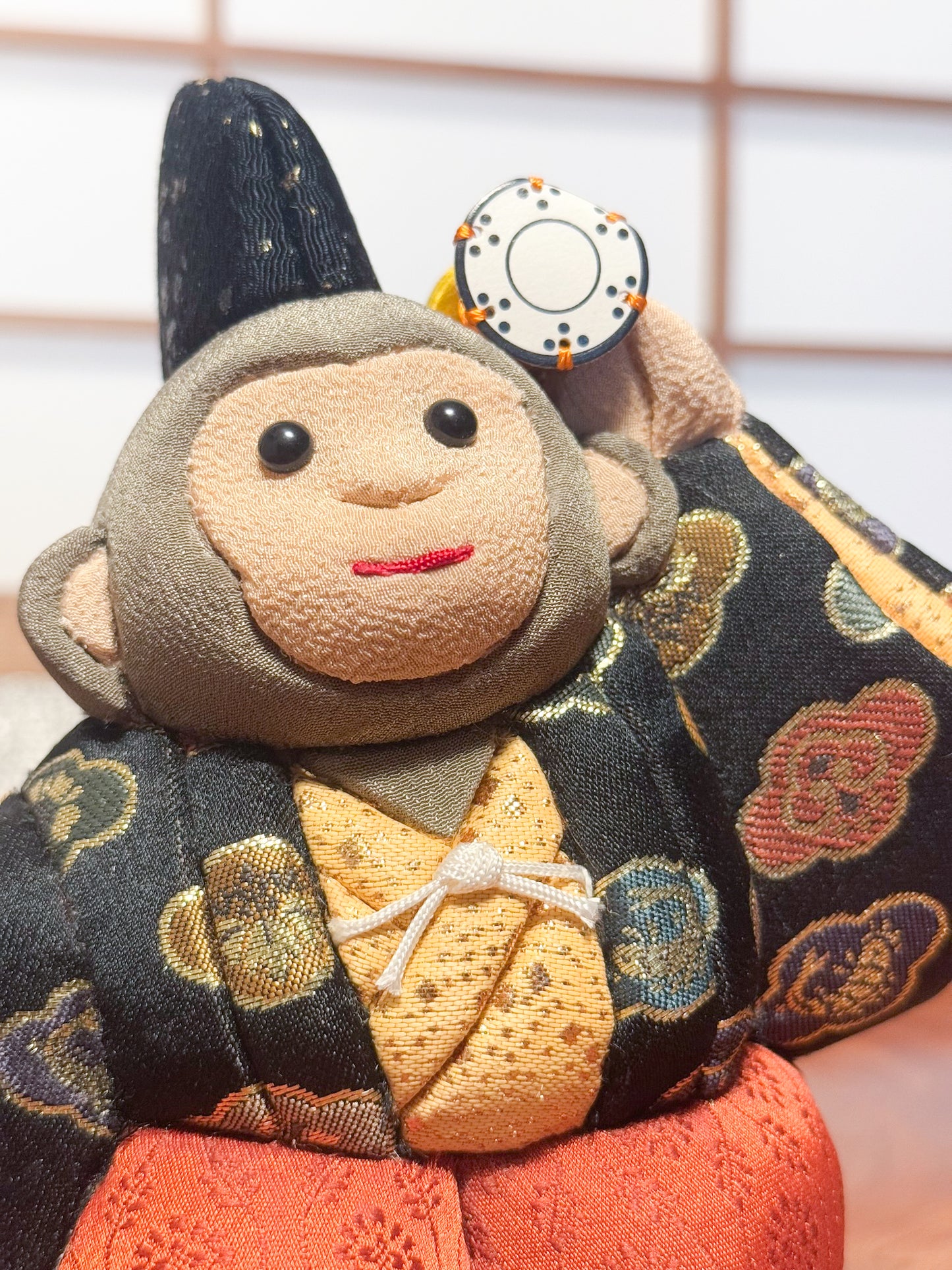 poupée japonaise kimeomi représentant un singe en habits traditionnels et portant un petit tambour, gros plan sur le visage souriant