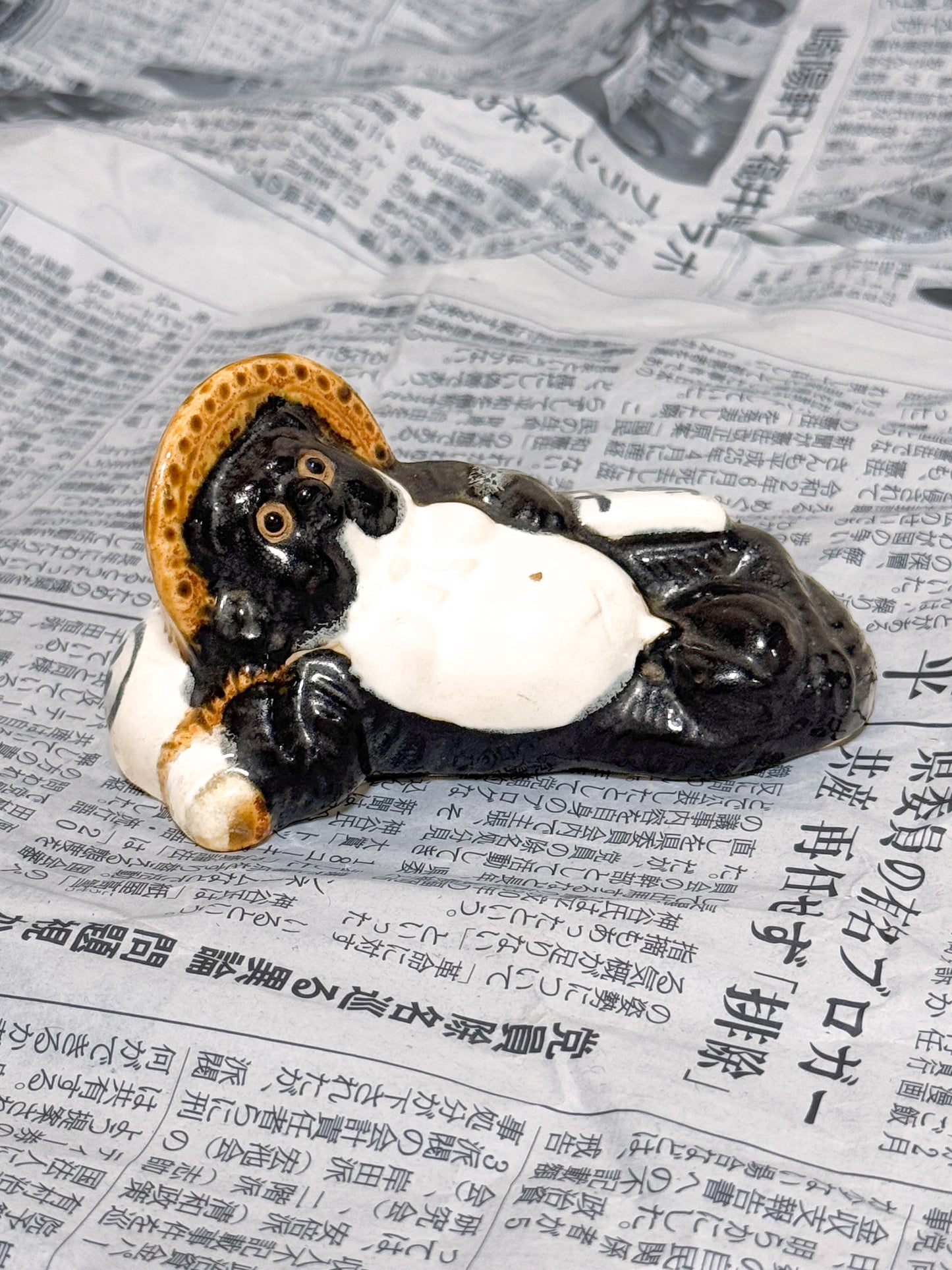 Figurine en céramique d’un tanuki allongé sur une bouteille de saké portant le kanji 福, symbole de bonheur et de prospérité au Japon