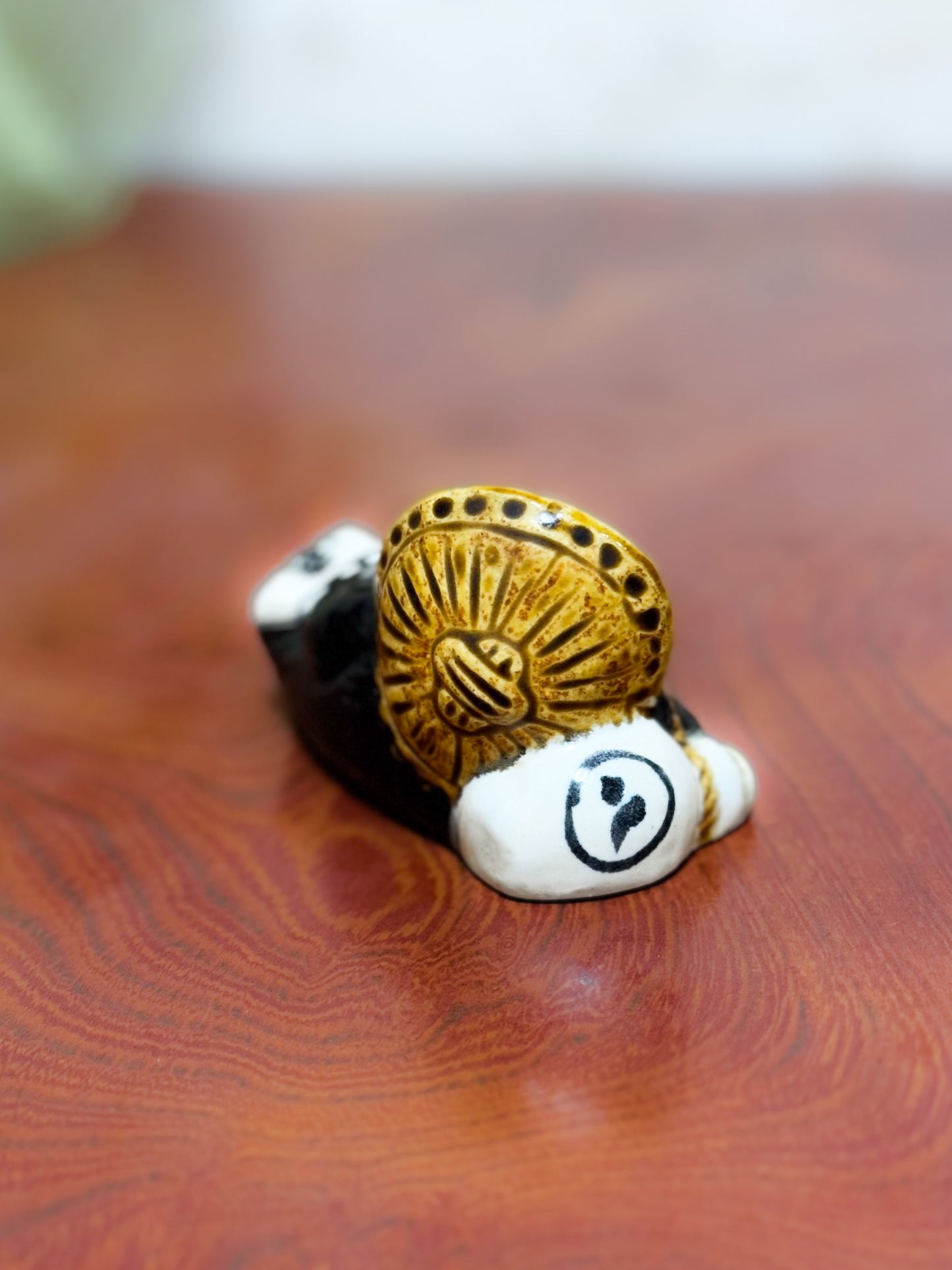 Figurine en céramique d’un tanuki allongé sur une bouteille de saké portant le kanji 福, symbole de bonheur et de prospérité au Japon, gros plan sur la bouteille de sake