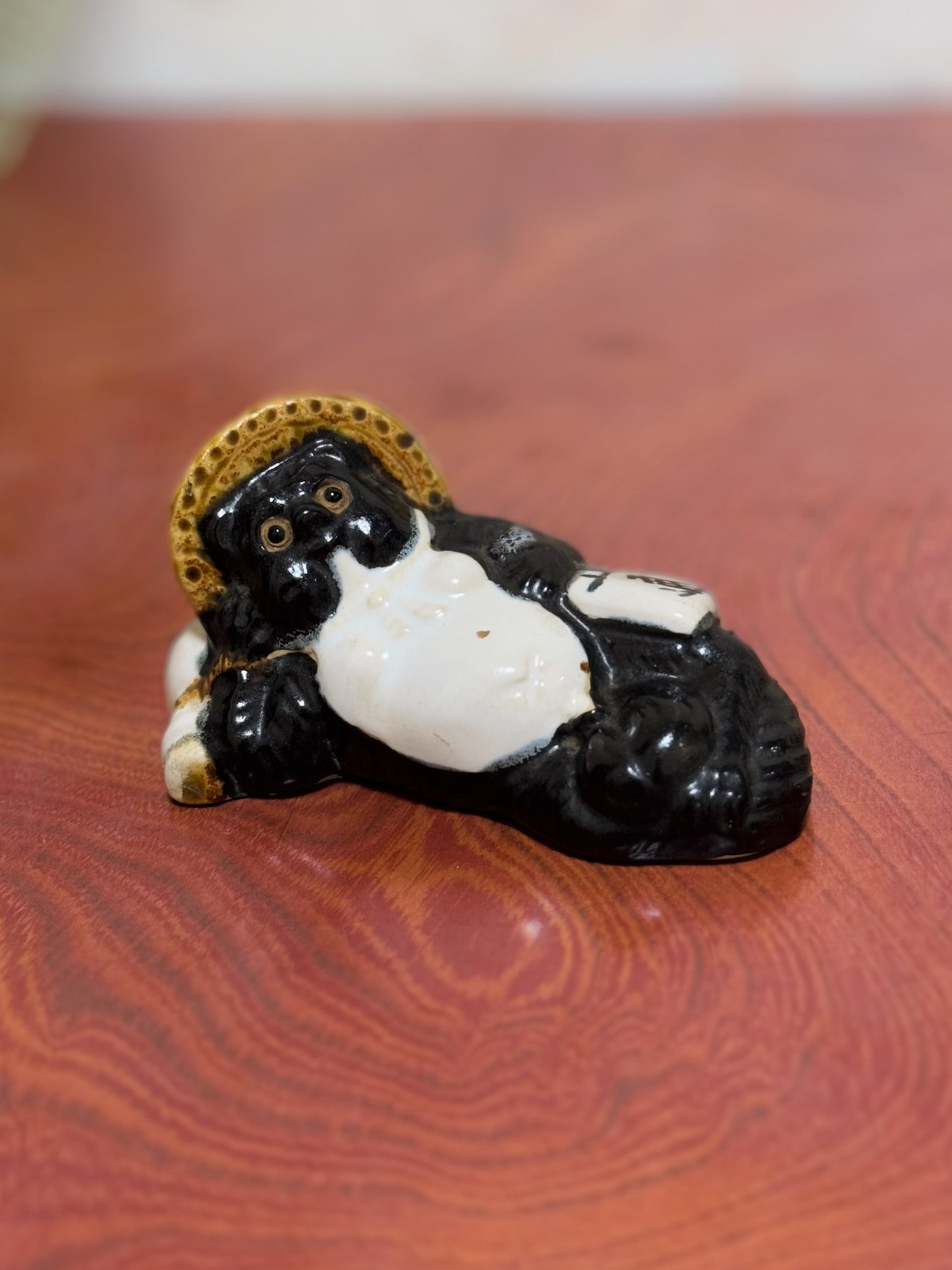 Figurine en céramique d’un tanuki allongé sur une bouteille de saké portant le kanji 福, symbole de bonheur et de prospérité au Japon, vu de 3/4