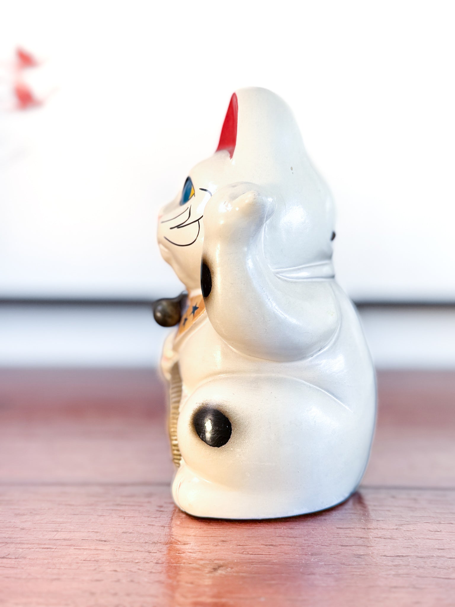 Maneki Neko blanc vintage avec clin d’œil, pièce dollar et motifs étoilés façon drapeau américain, profil gauche