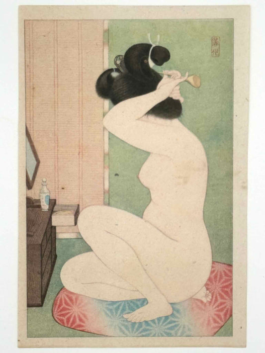 Lithographie Japonaise portrait de femme nue après le bain, assise de profil sur coussin rouge et bleu, en train de mettre une épingle dans ses cheveux face à un miroir.