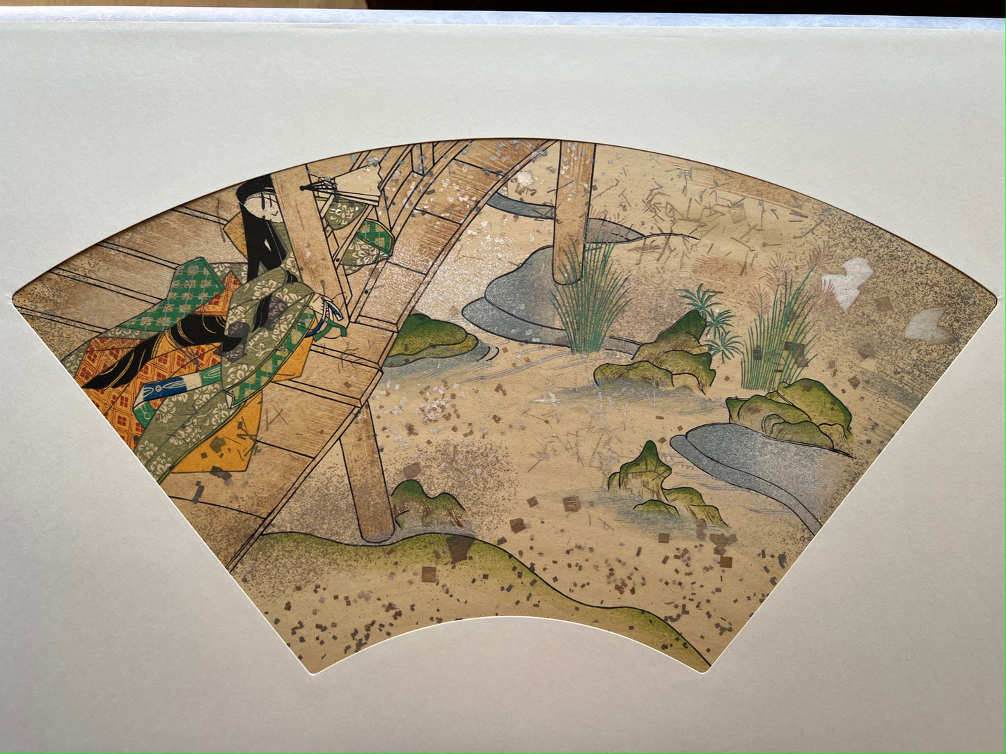 Estampe japonaise en forme d'éventail parsemée de fragments d'or et d'argent, femme assoupie sur une terrasse au-dessus d'une rivière, série sutra du lotus.