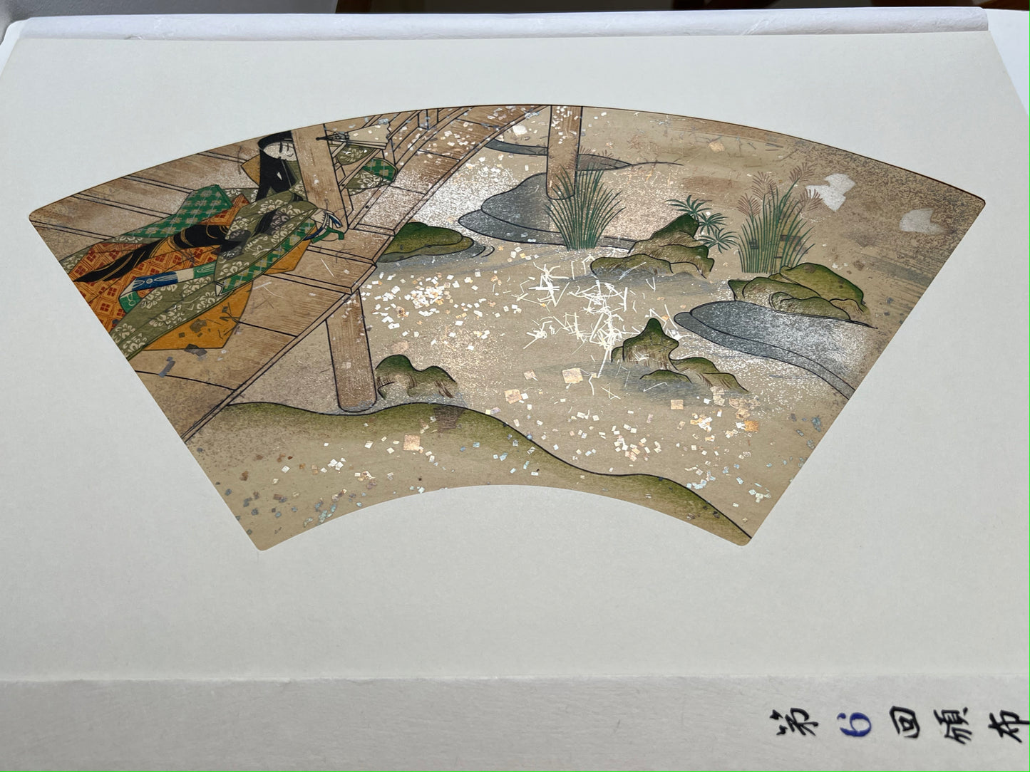 Estampe japonaise en forme d'éventail parsemée de fragments d'or et d'argent, femme assoupie sur une terrasse au-dessus d'une rivière, série sutra du lotus n°6 écrit en japonais dans le coin inférieur droit.