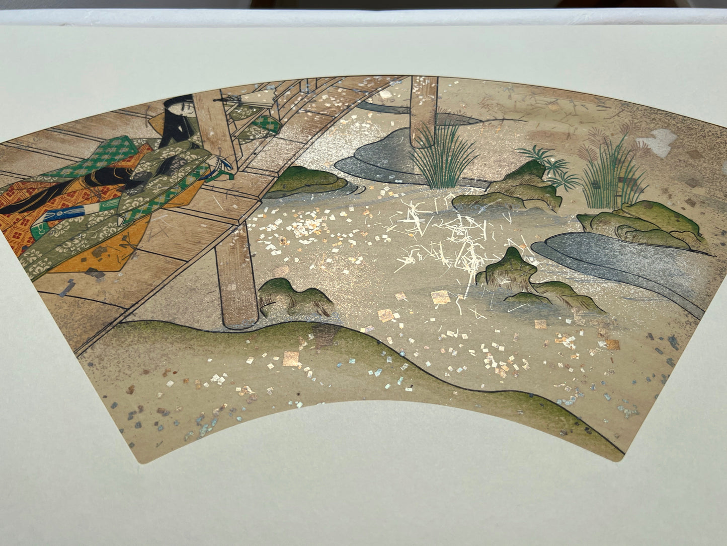 Estampe japonaise en forme d'éventail parsemée de fragments d'or et d'argent, femme assoupie sur une terrasse au-dessus d'une rivière, série sutra du lotus.