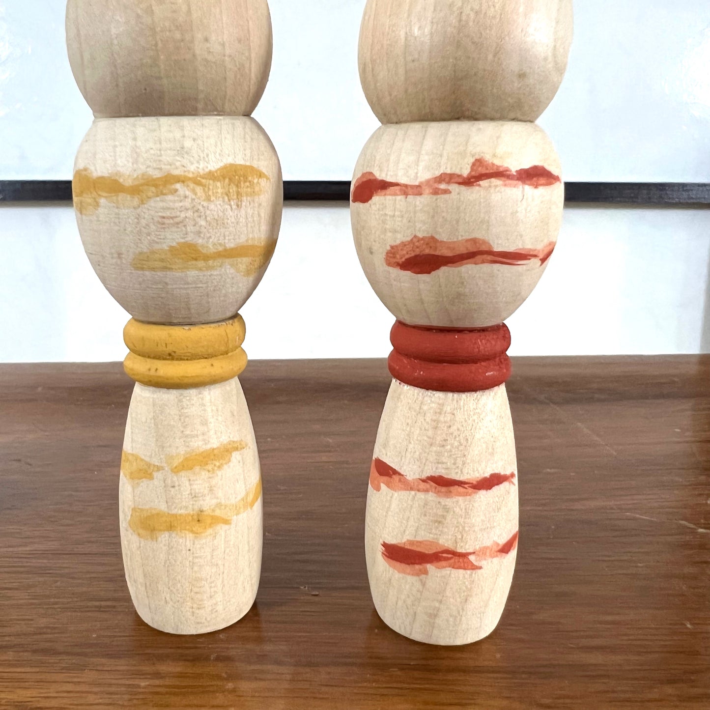 kokeshi, poupée japonaise en bois, couple avec ceinture rouge pour la femme et jaune pour l'homme, gros plan sur les corps peints
