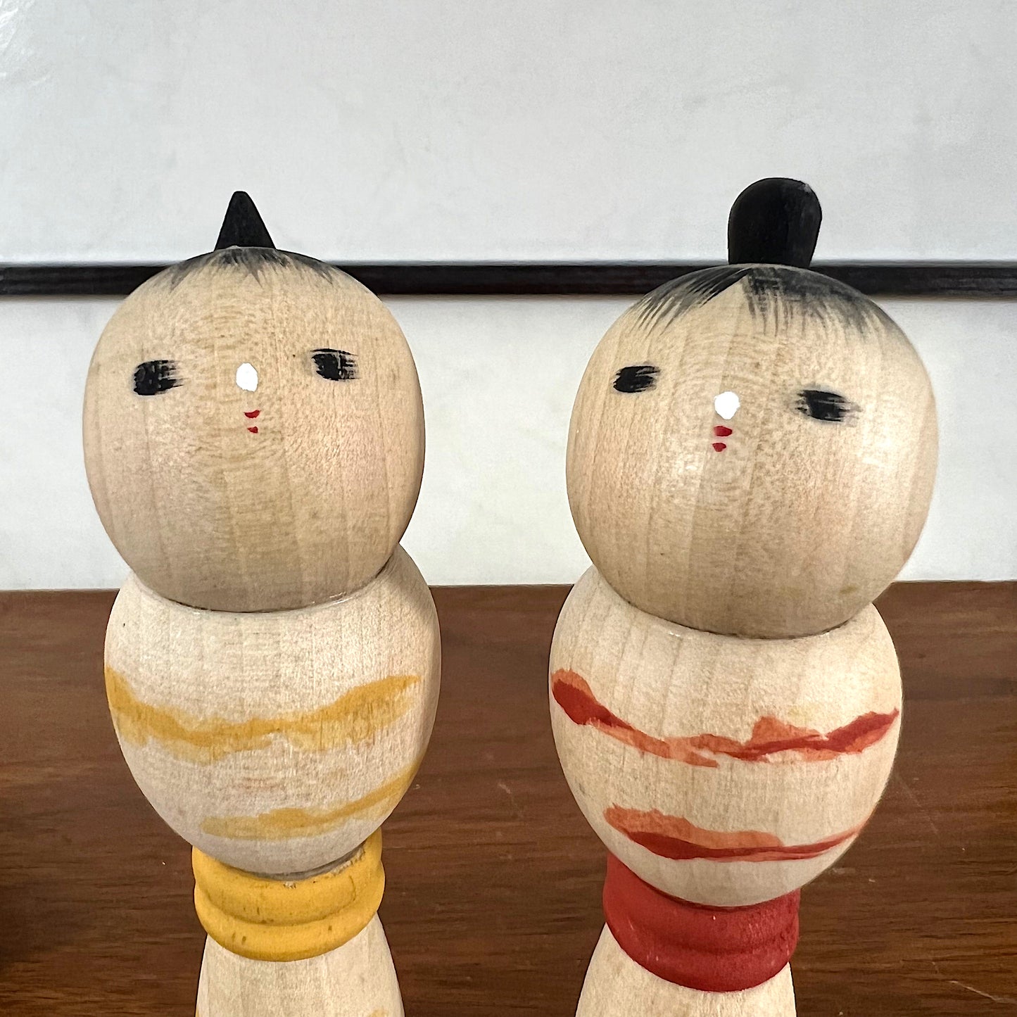 kokeshi, poupée japonaise en bois, couple avec ceinture rouge pour la femme et jaune pour l'homme, gros plan sur les visage