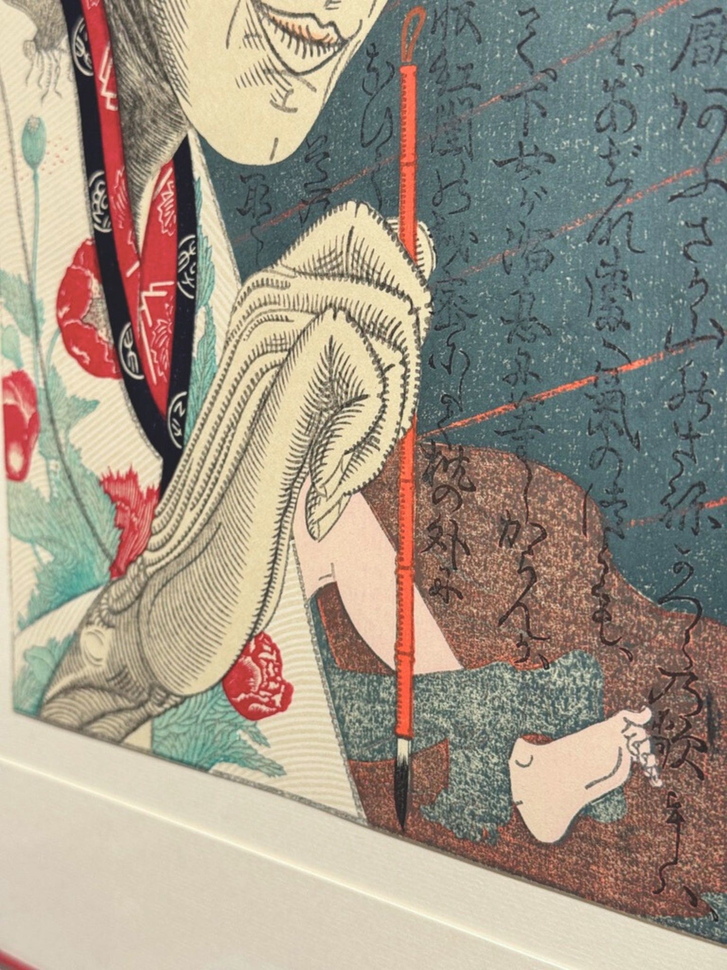 Estampe japonaise contemporaine de Tsuruya Kōkei représentant le portrait d’Utamaro en train de peindre, tenant un pinceau rouge sur fond calligraphié, gros plan sur la main tenant un pinceau et pied