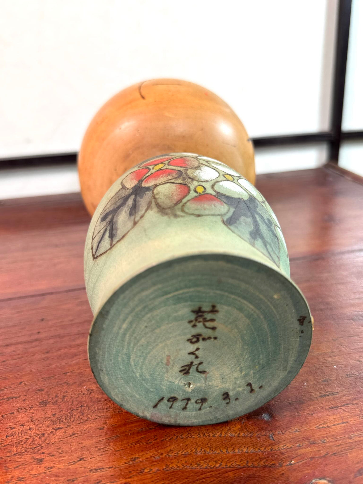 Kokeshi Yuji Kawase de 1979 à décor floral vert, rouge et blanc, la signature et la date au dessous