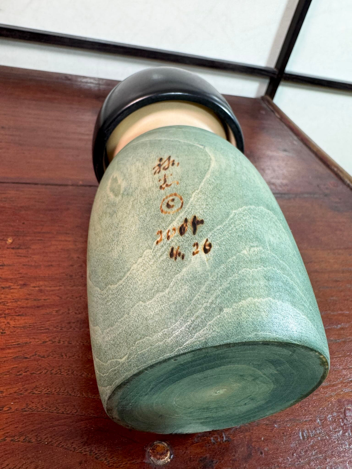 Kokeshi Yuji Kawase Asanoha au kimono vert et bleu, la signature et la date grvées sur le dos