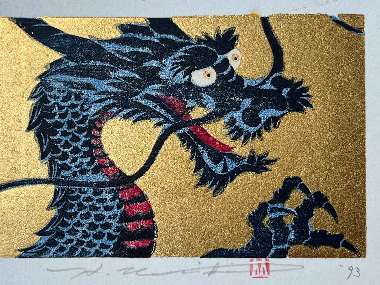 estampe japonaise dragon bleu gueule ouverte sur fond or, gros plan de la tête et signature de l'artiste