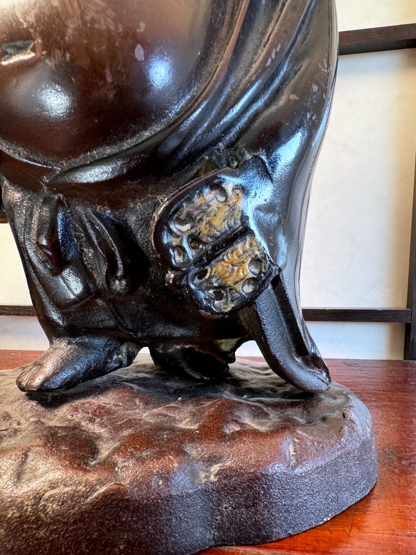 statuette en bronze cuivré de Hotei, dieu du bonheur, gros plan sur l'éventail et les pieds