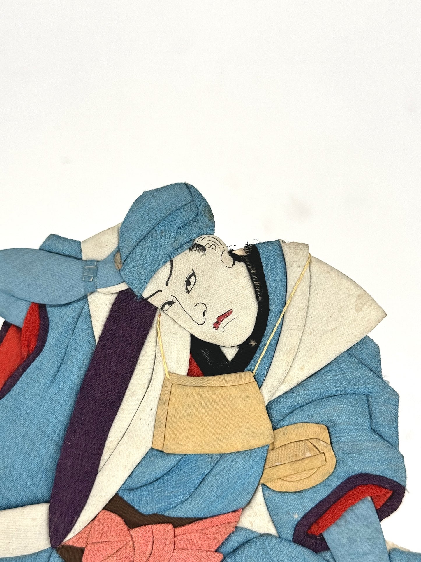 Okiyage japonais représentant un danseur en kimono bleu en tissu, dans une posture dynamique, avec visage peint à la main et accessoires suspendus, le visage