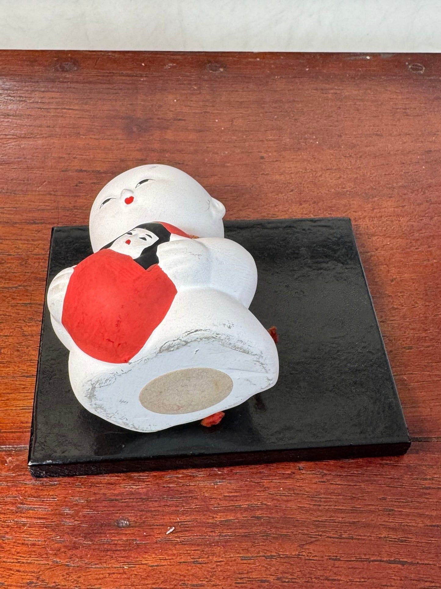 Gosho Ningyō en céramique tenant un Hime Daruma rouge japonais, vu de dessous